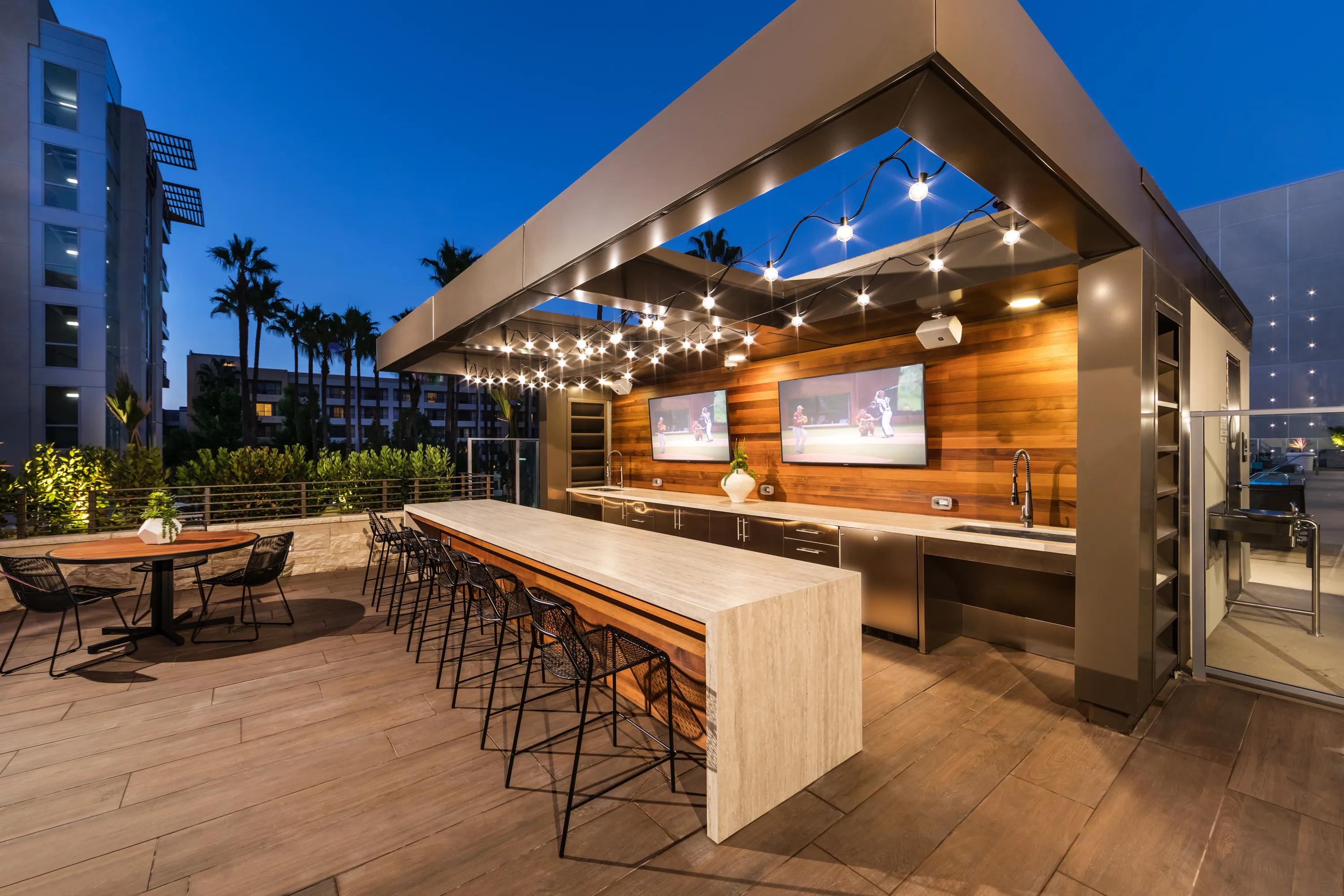 Outdoor lounge with bar seating, flat screen TVs, and food prep areas 580 anton apartments in costa mesa