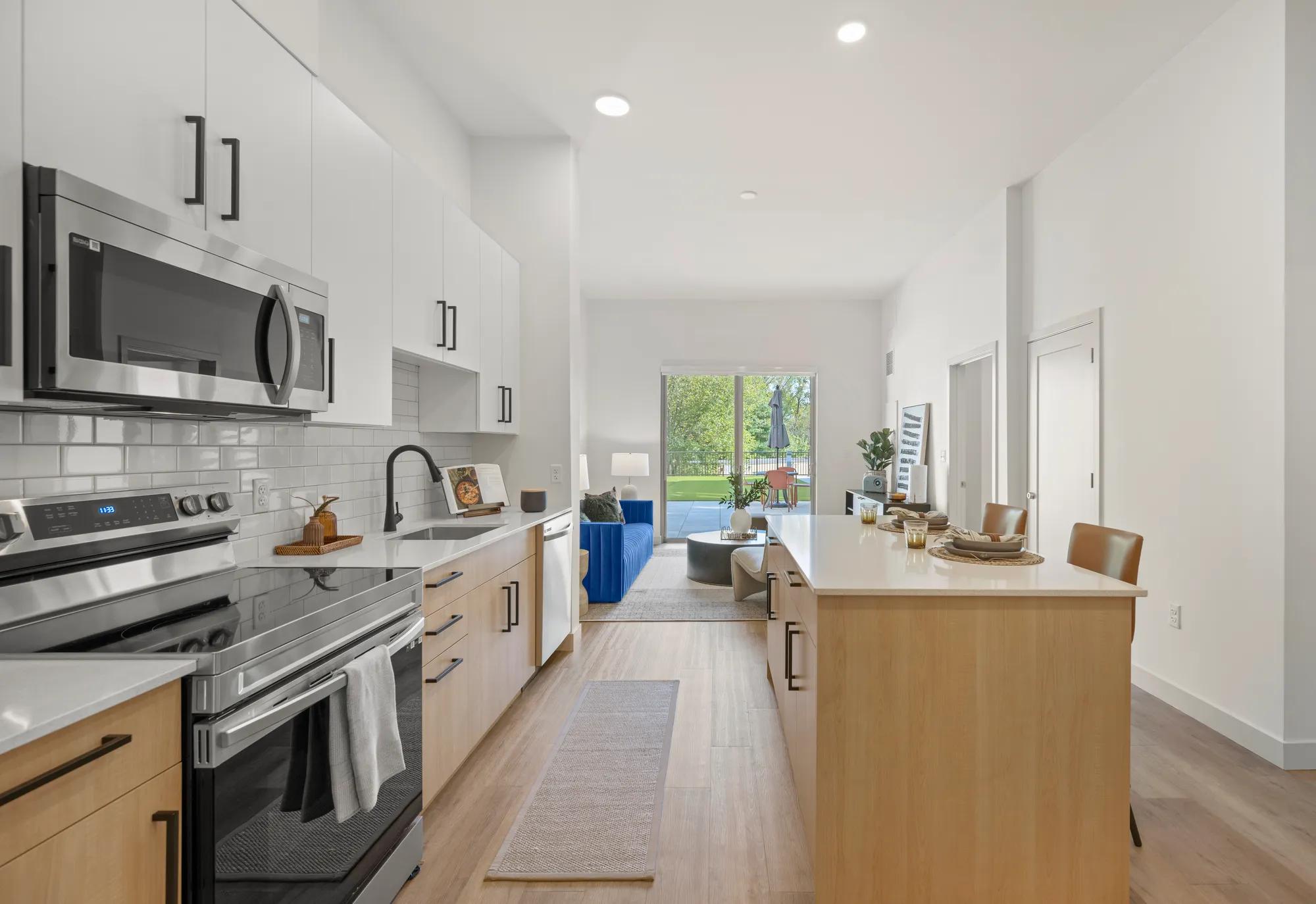 kitchen with two toned cabinetry and stainless steel appliances looking onto living area at modera newton apartment homes for rent in ma