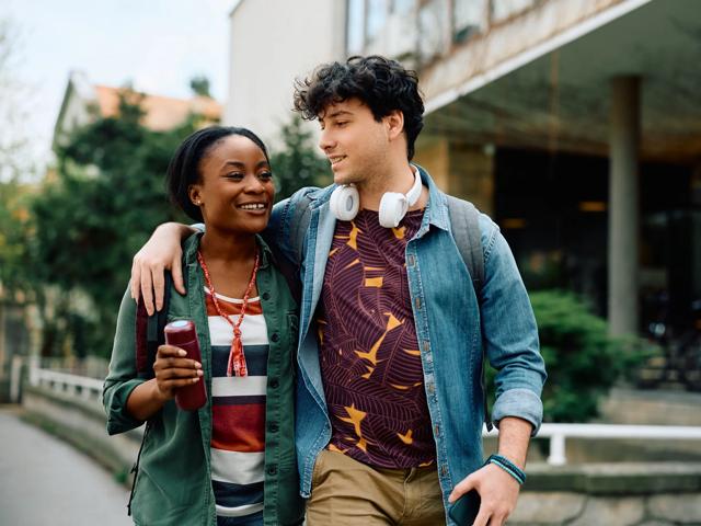 Multiracial student couple walking embraced through the campus babson college near modera needham