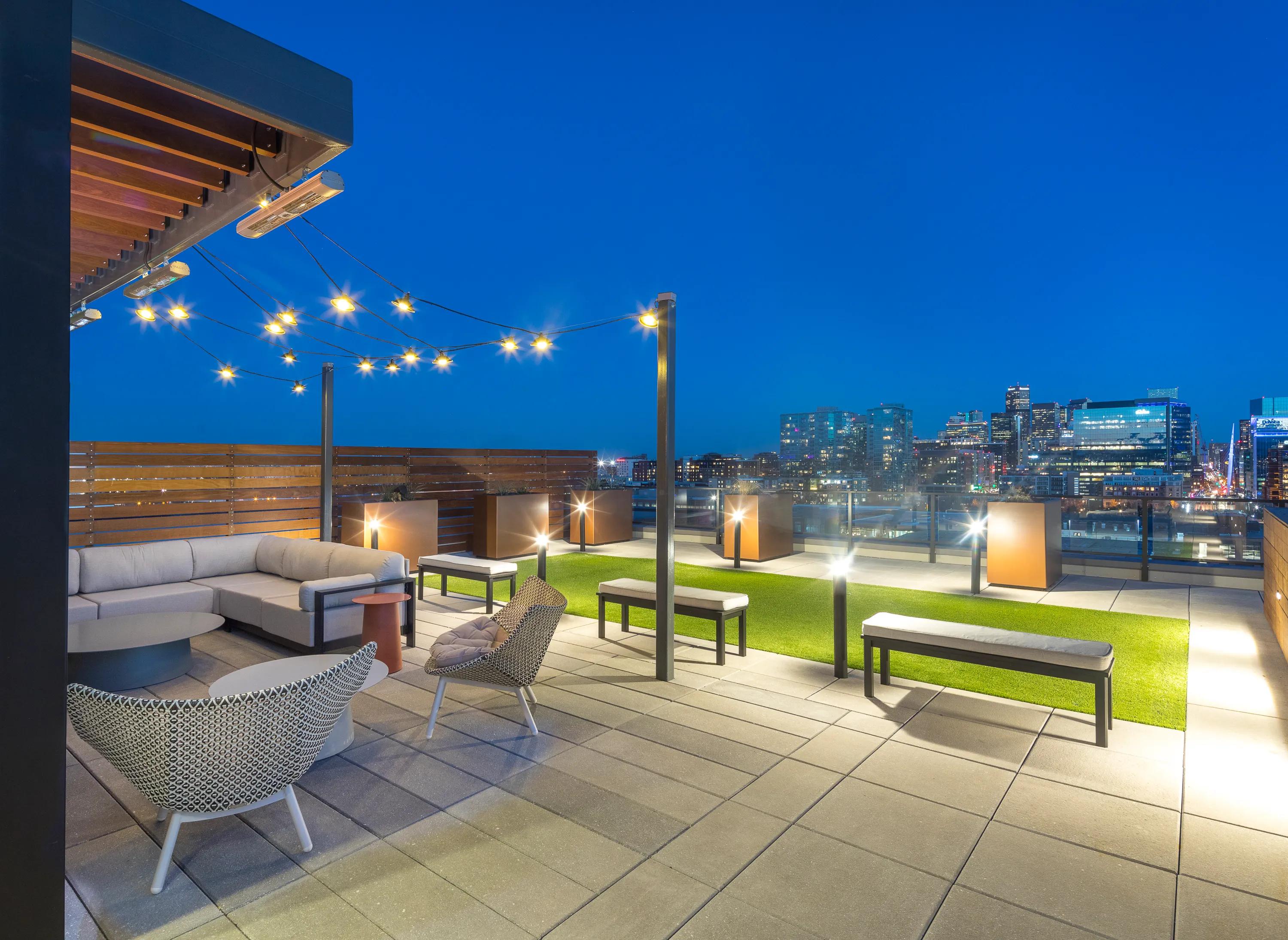 Private rooftop overlooking stunning city views with lounge seating under trendy lighting and outdoor heaters modera lohi apartments in denver co