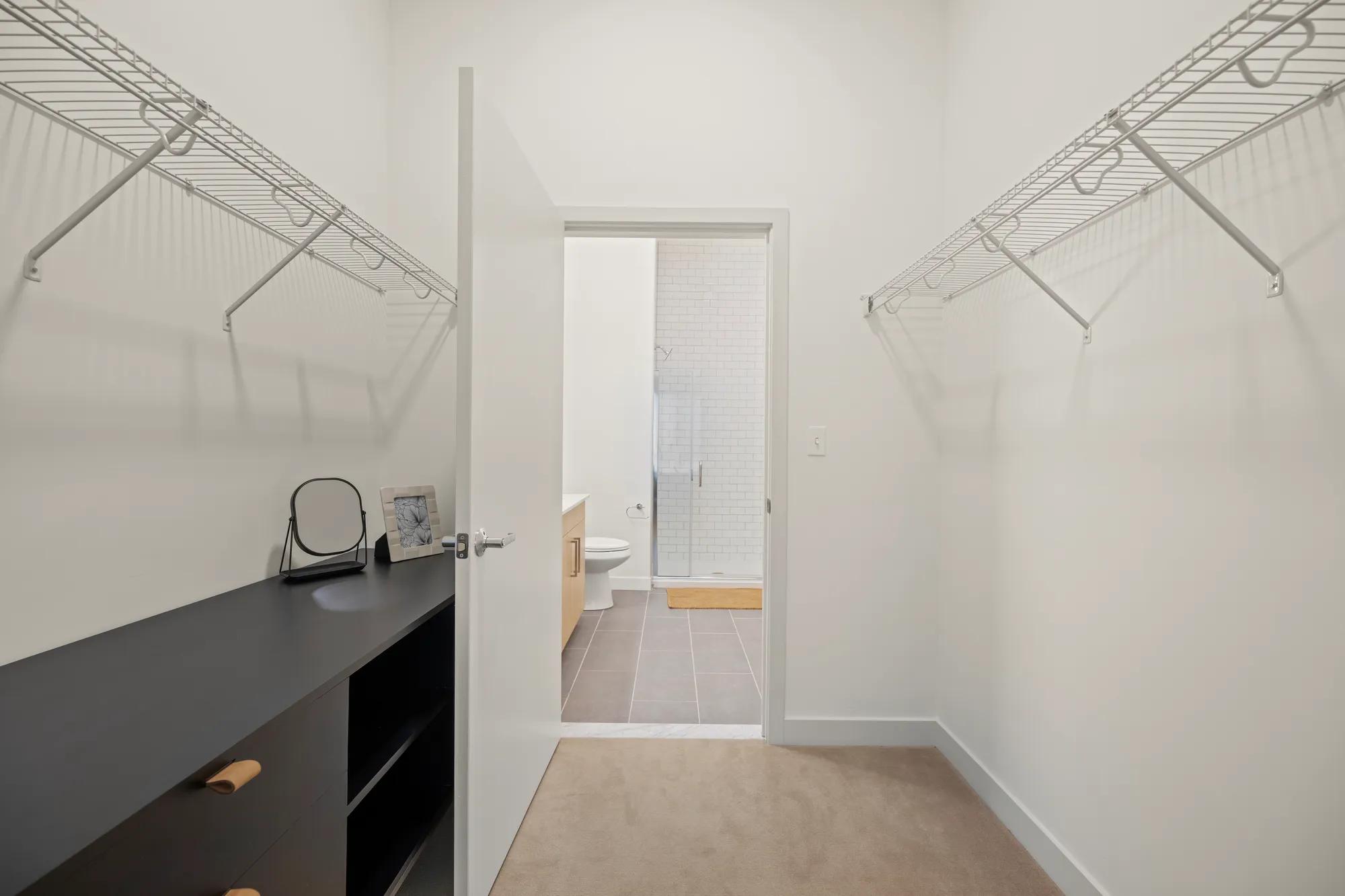 closet with built in shelving looking into bathroom with shower at modera newton apartment homes for rent in ma