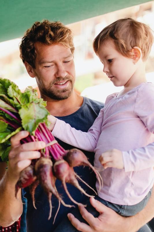 father and young child at a local farmers market holding radishes modera st paul dallas tx apartments