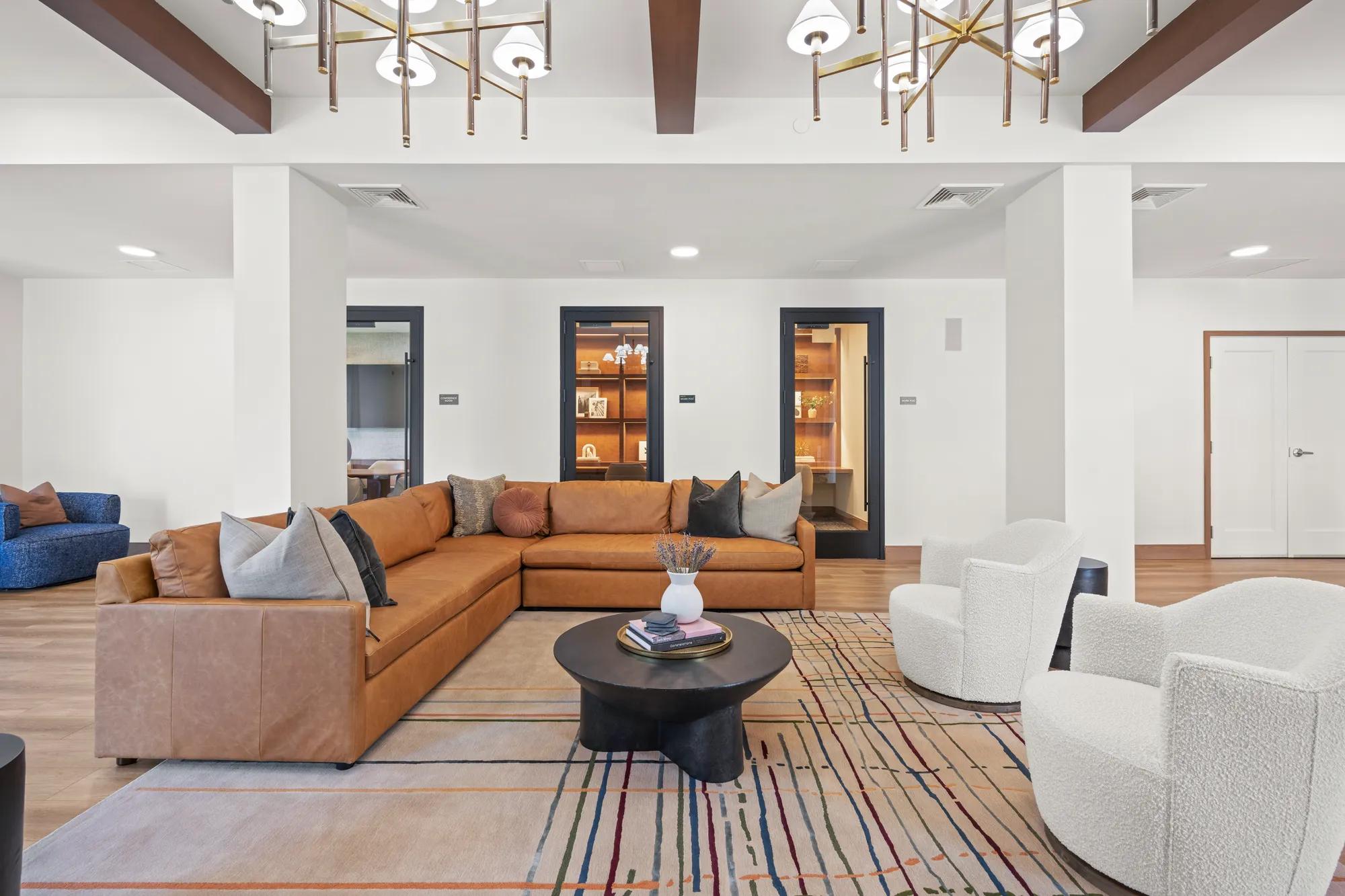 large section tan leather couch in clubhouse room at modera newton apartment homes for rent in ma