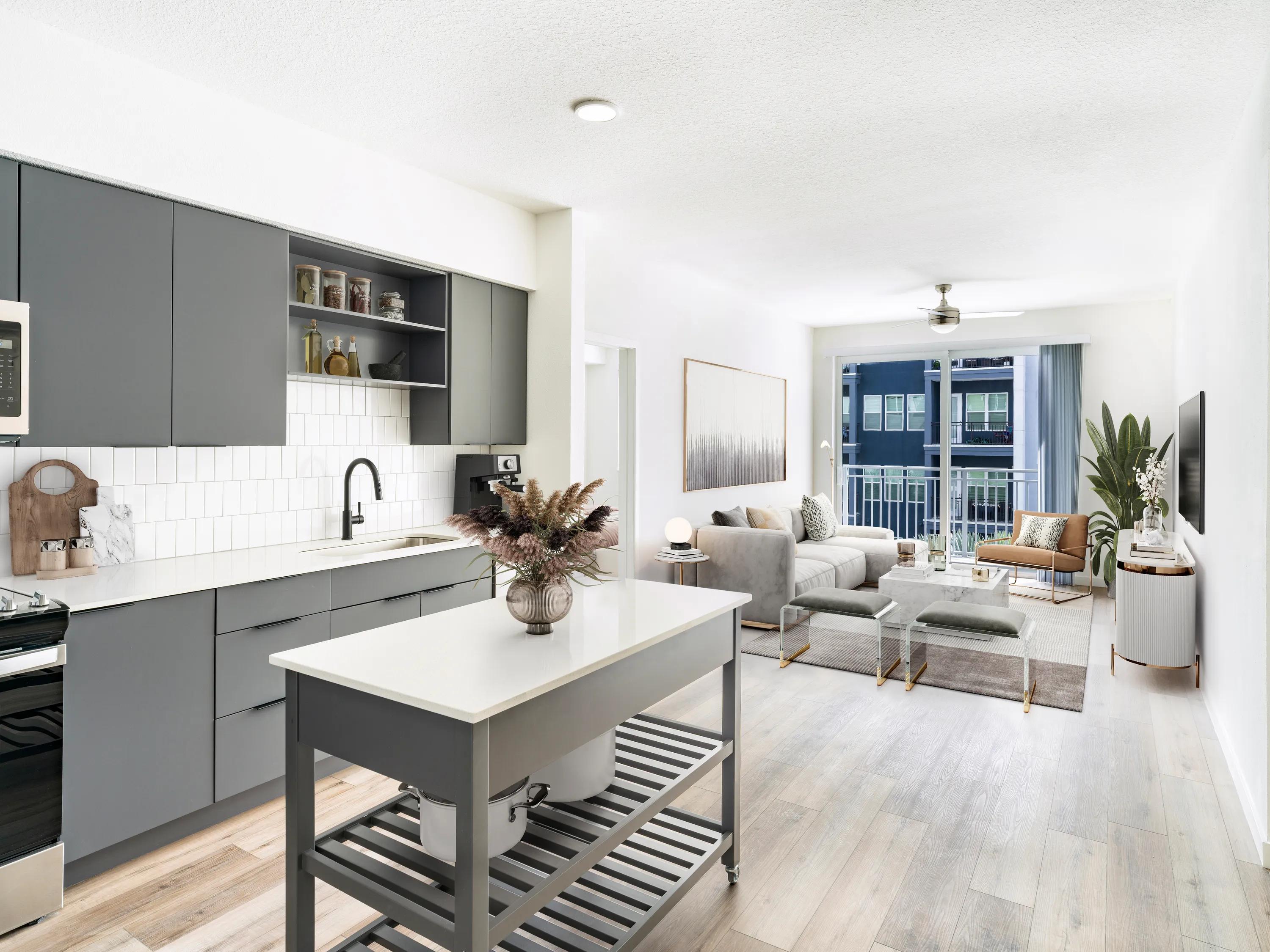 kitchen with dark cabinets overlooking living area with hardwood style flooring modera encore apartments in tampa fl