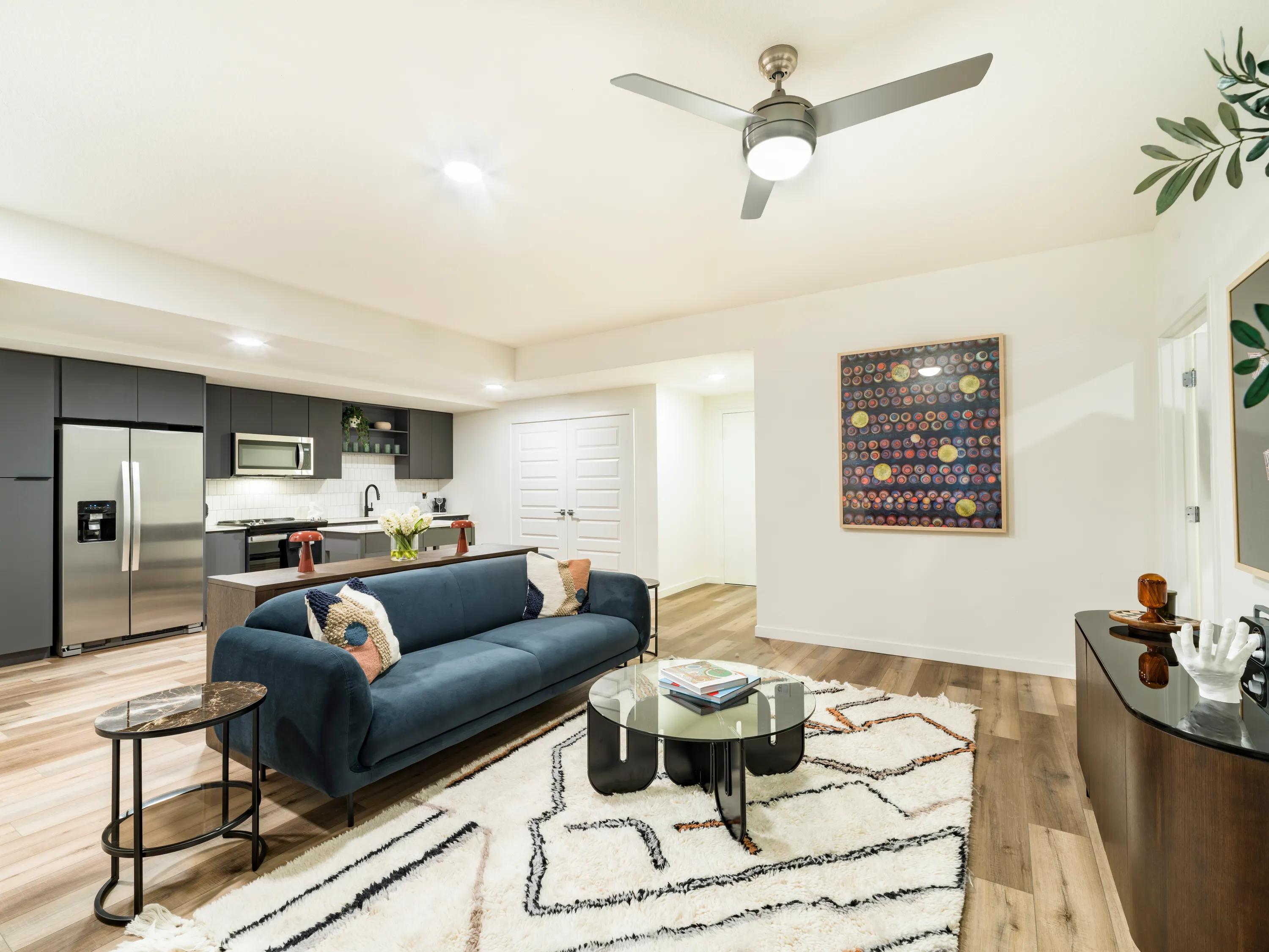 Open-concept apartment home with wood-style flooring, a spacious living room, contemporary finishes, stainless steel appliances, and a modern kitchen at Modera Encore apartments in Tampa, FL.