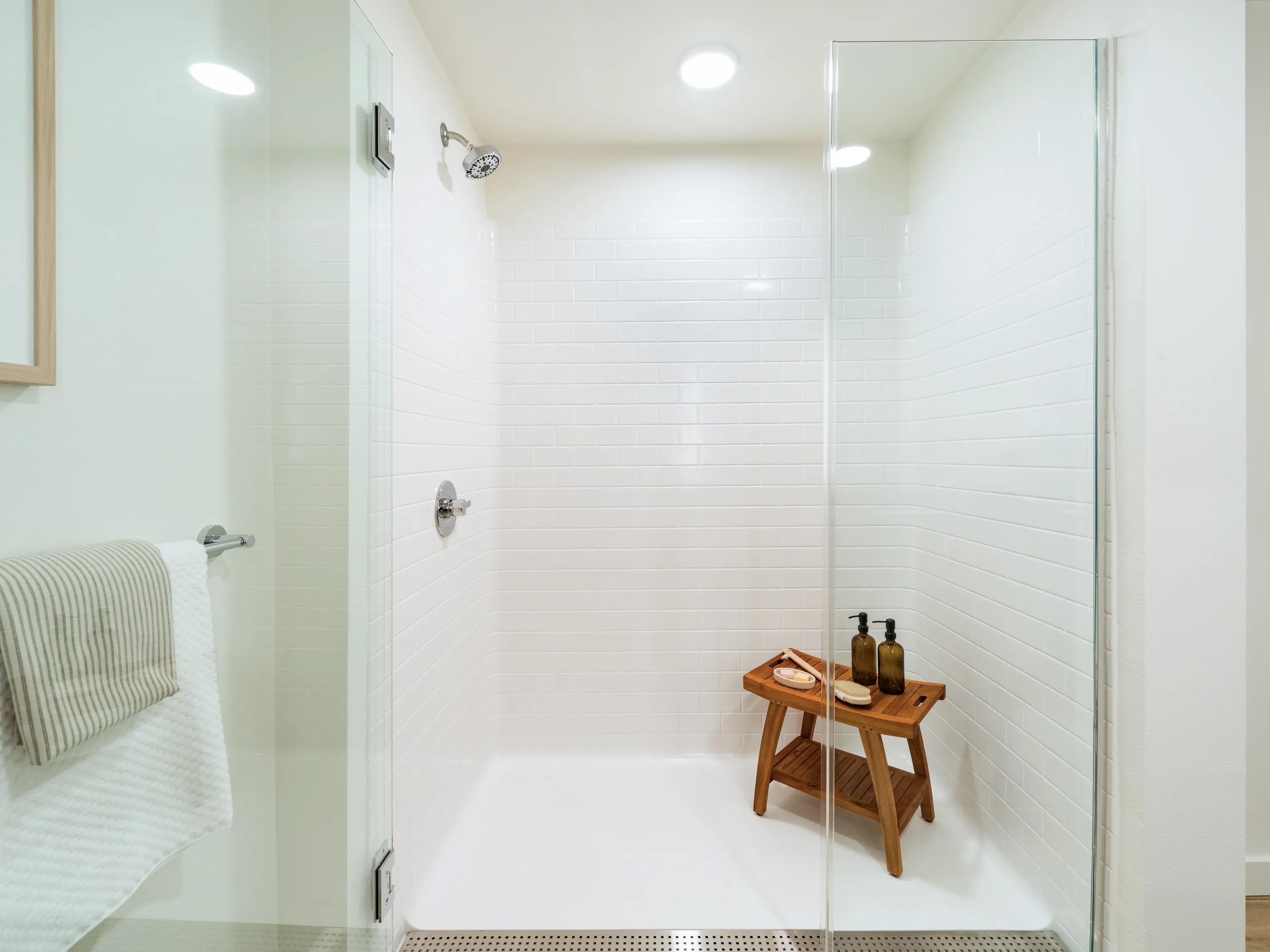 Frameless glass walk-in shower with white subway tile surround, modern fixtures, and a spacious spa-inspired design at Modera Melrose apartments for rent in Oceanside, CA.