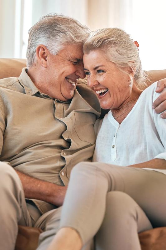mature couple sitting on couch embracing modera melrose apartments in oceanside ca