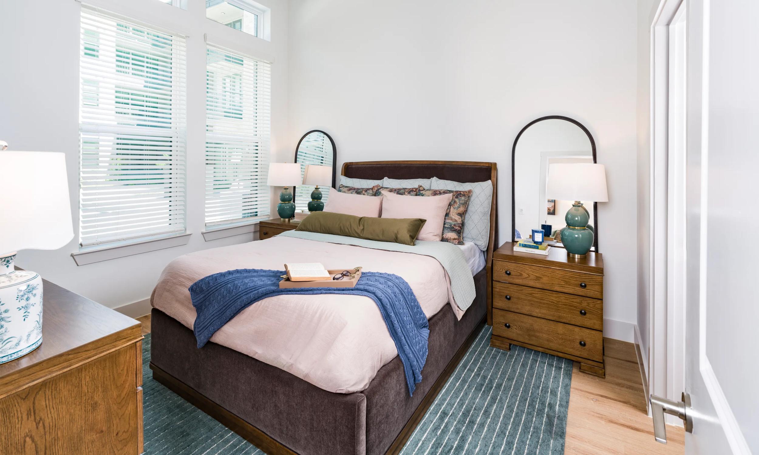Primary bedroom with tall windows, and warm wood flooring, creating a bright and comfortable retreat modera walsh heights