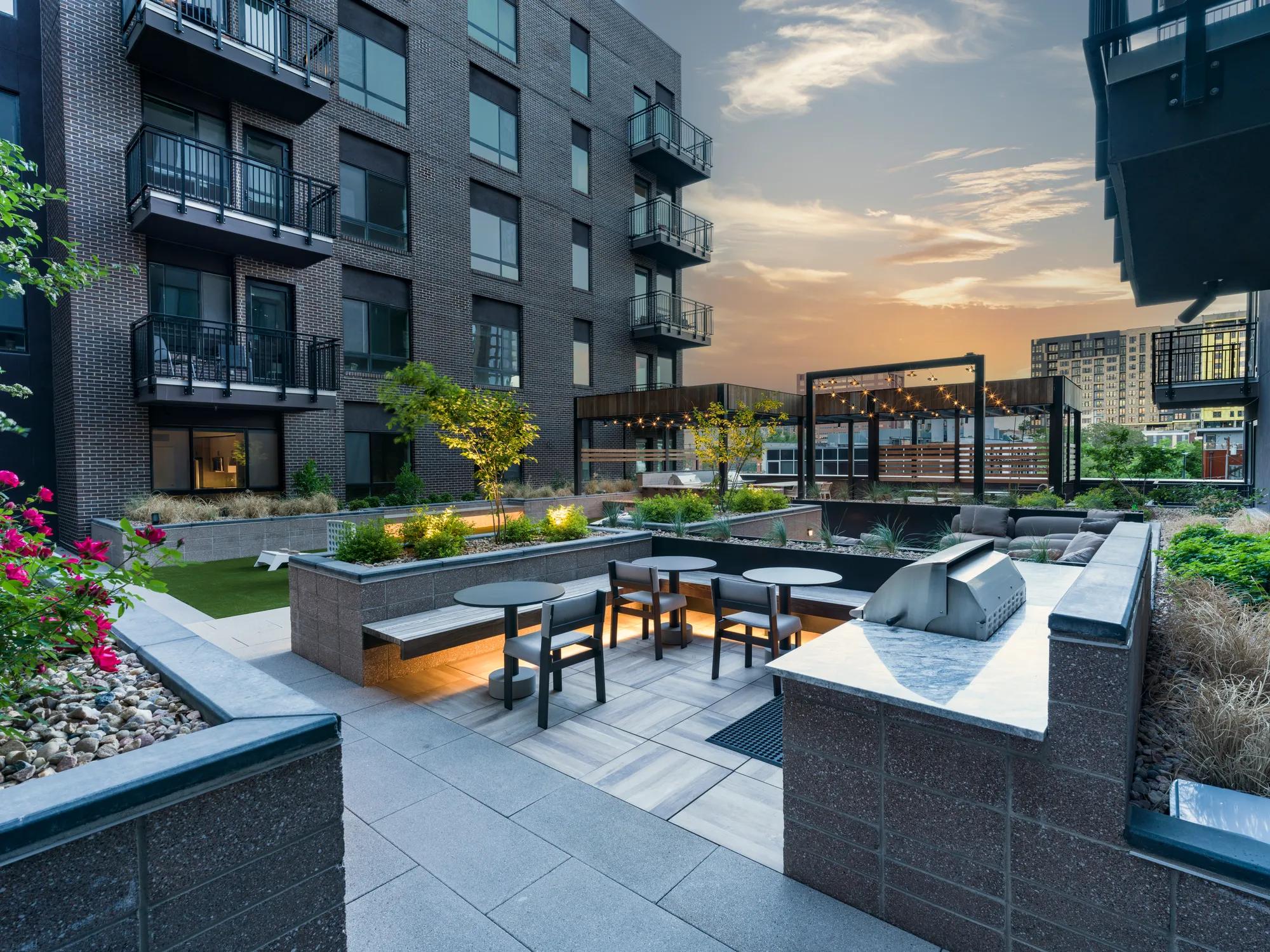 outdoor dining with grill and ambient lighting at dusk modera golden triangle apartment homes for rent in denver co