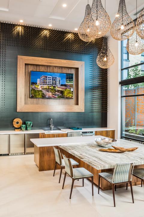 Luxurious modern kitchen interior with sleek wooden cabinets, elegant pendant lighting, and large windows offering ample natural light.
