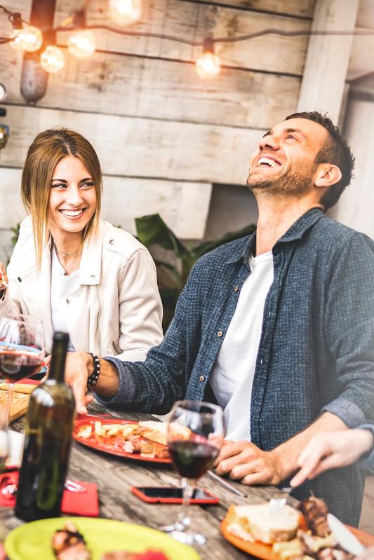 couple sitting at table with group of friends dining and laughing alister oak hill apartments in austin