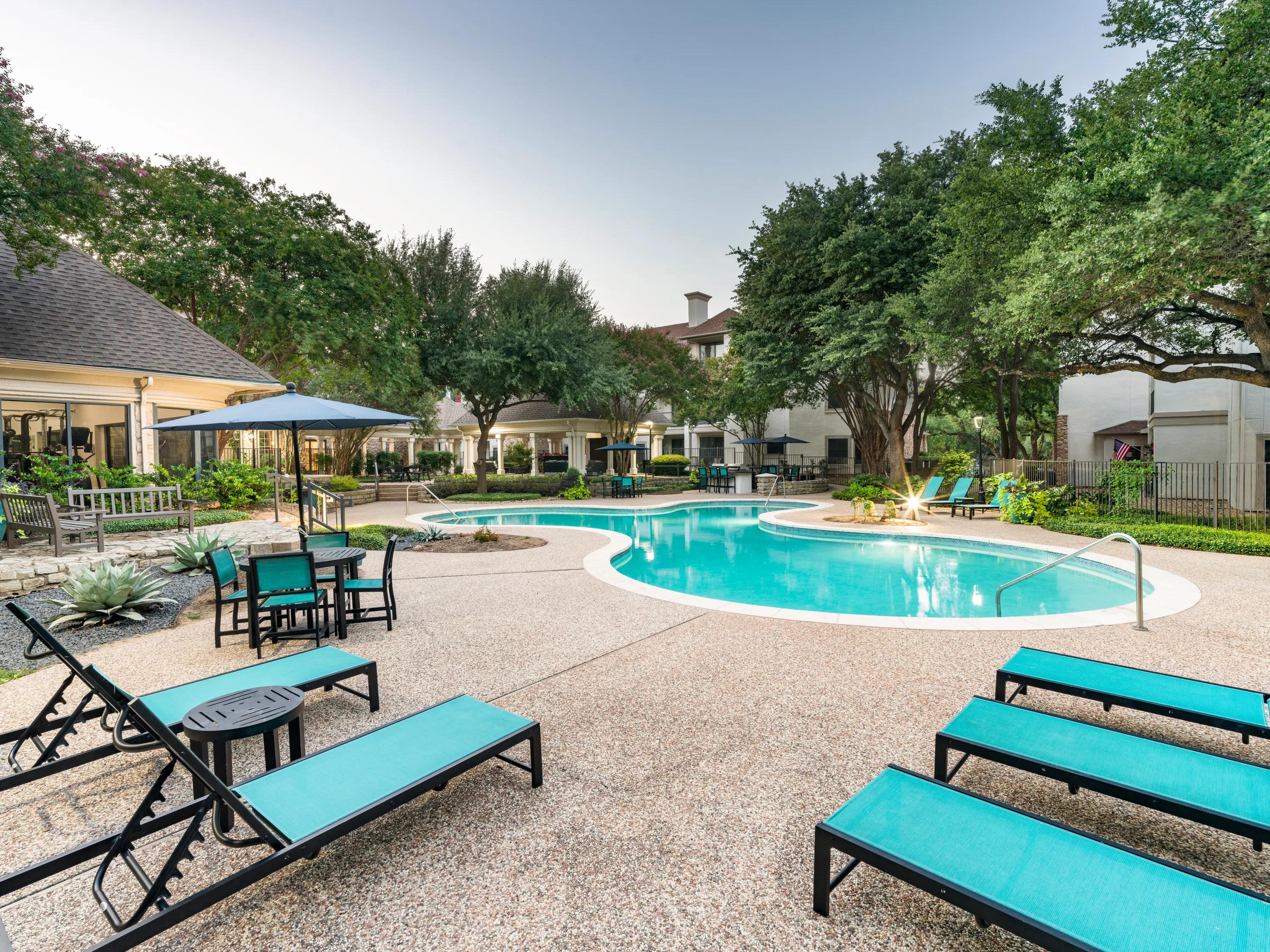 outdoor pool with large trees on sundeck alister sunset valley apartment homes for rent in austin tx