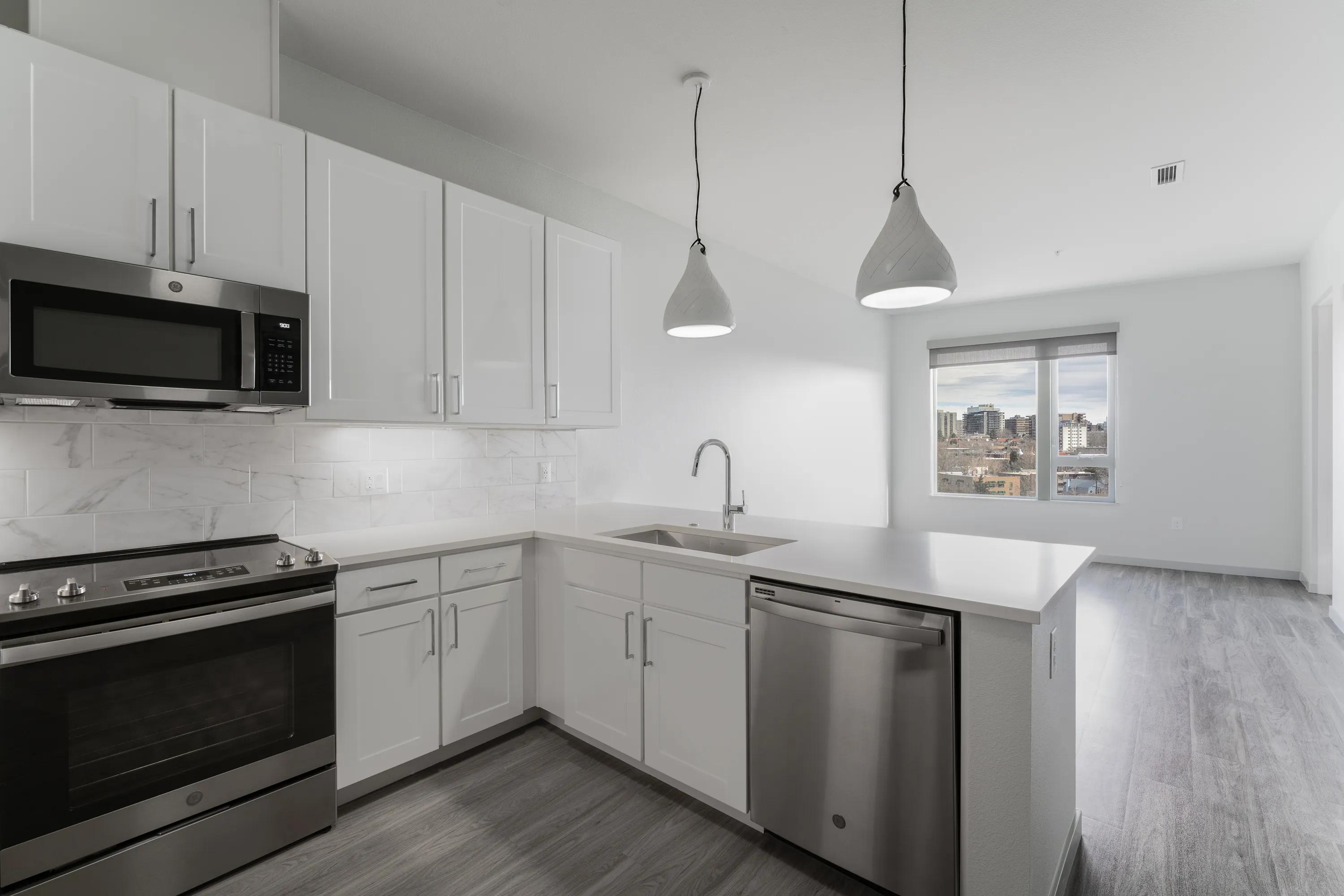 Open concept kitchen with marble backsplash and pendant lightingat Modera West Wash Park apartments in Denver.