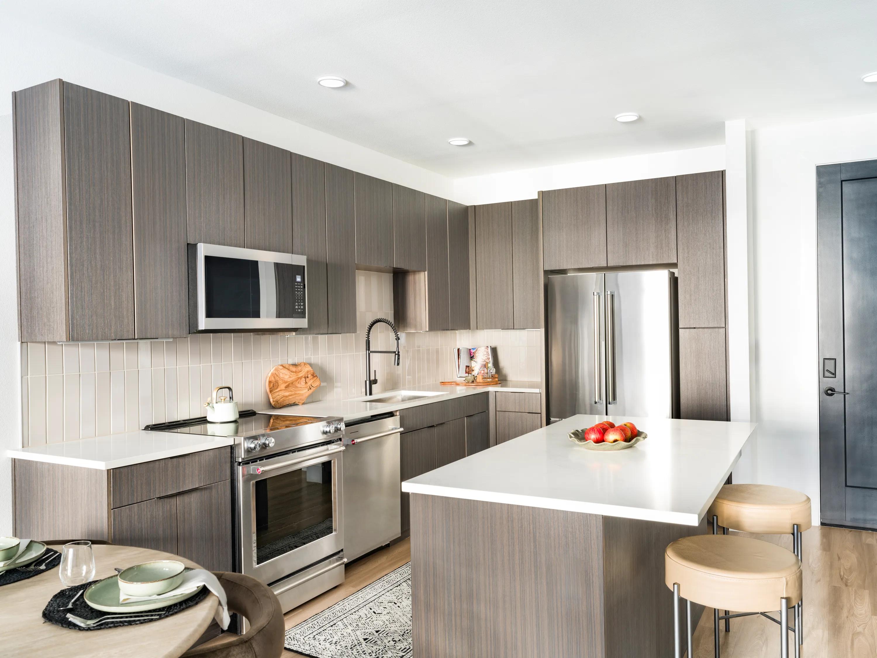 dark kitchen cabinetry with white quartz countertops, custom tile backsplash, and stainless steel appliances modera kierland apartments homes for rent in scottsdale z