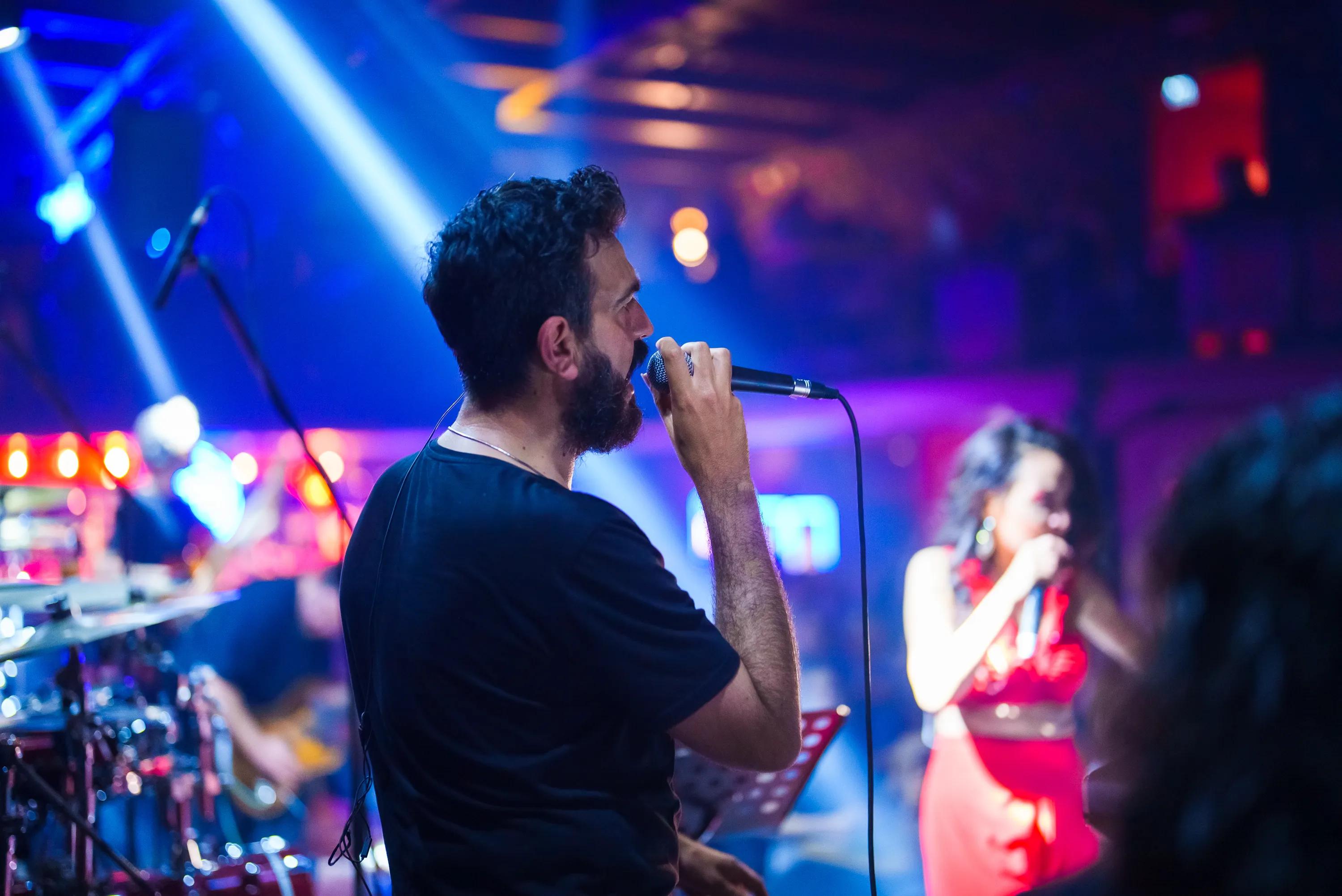 man singing into microphone onstage modera h street apartment homes for rent