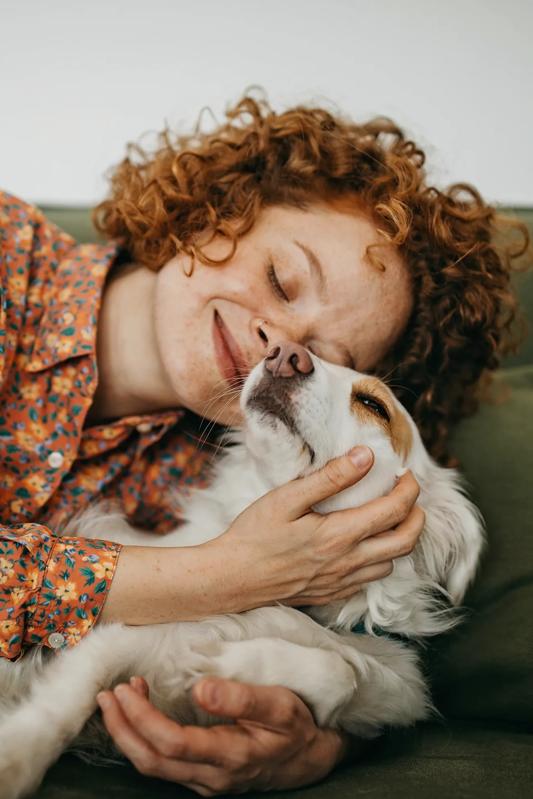 young woman hugging dog on couch and smiling modera chandler az