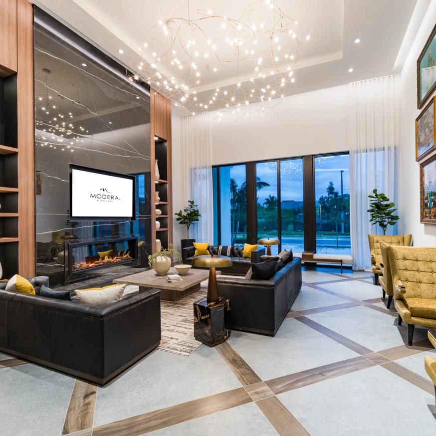 Sophisticated community room with high ceilings, chic modern decor, and expansive windows offering lush garden views.