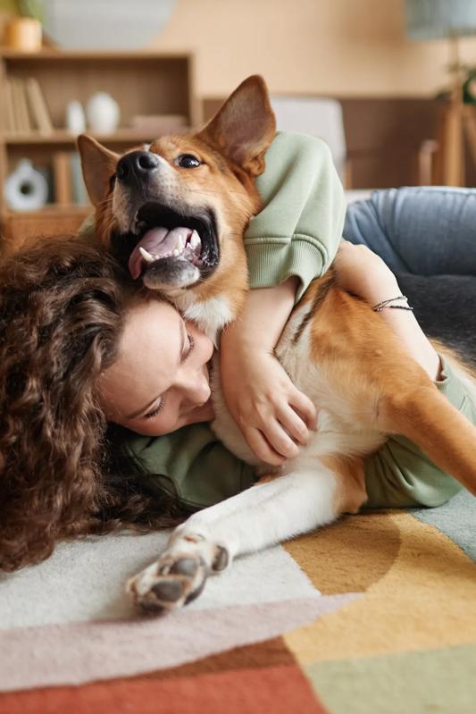 woman with curly hair laying on rug hugging dog and smiling modera mcgavock apartments in nashville tn