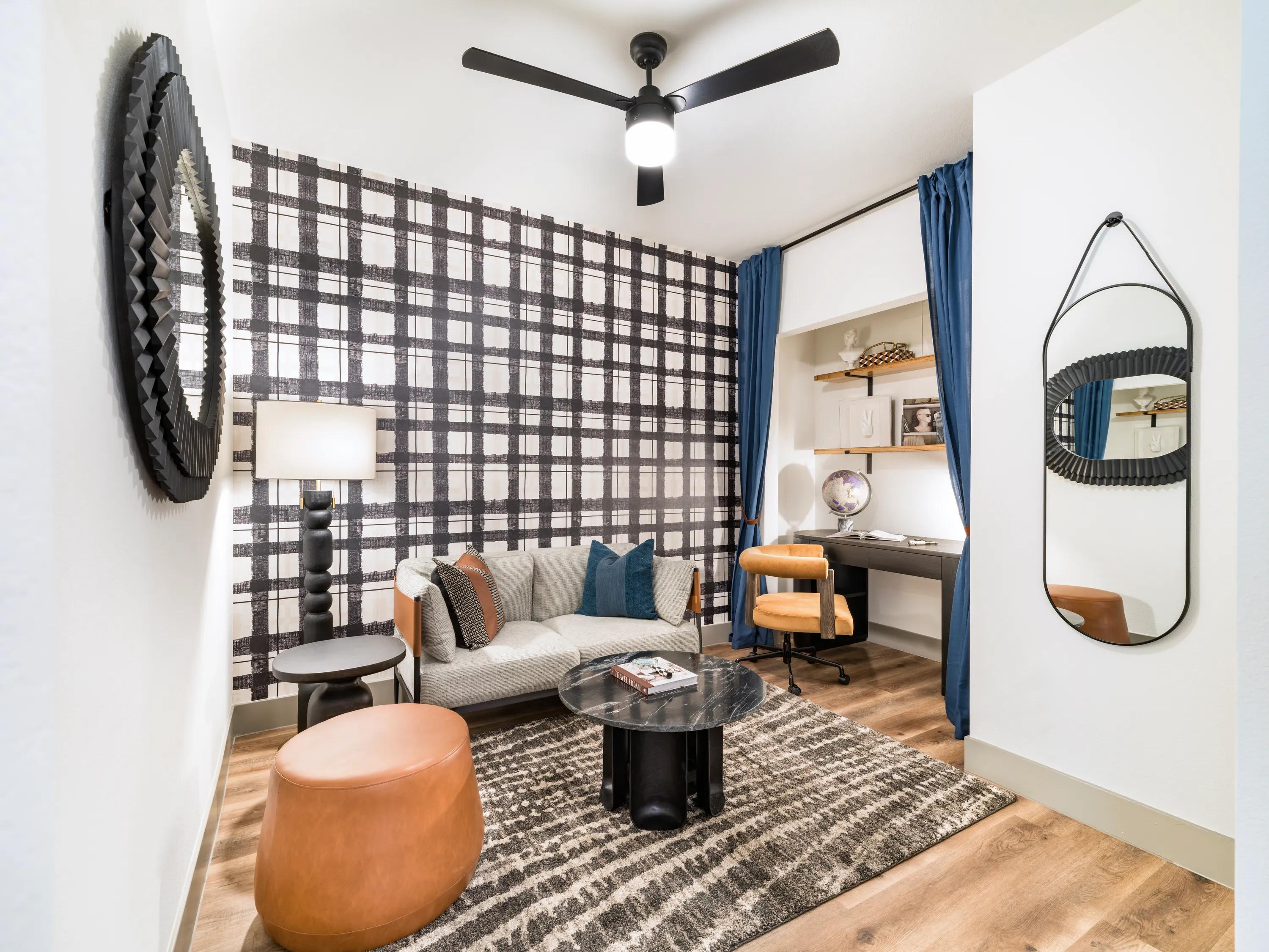 Multi-purpose den featuring a workspace, lounge seating, custom shelving, modern lighting, and wood-style flooring in apartments in Chandler, AZ.