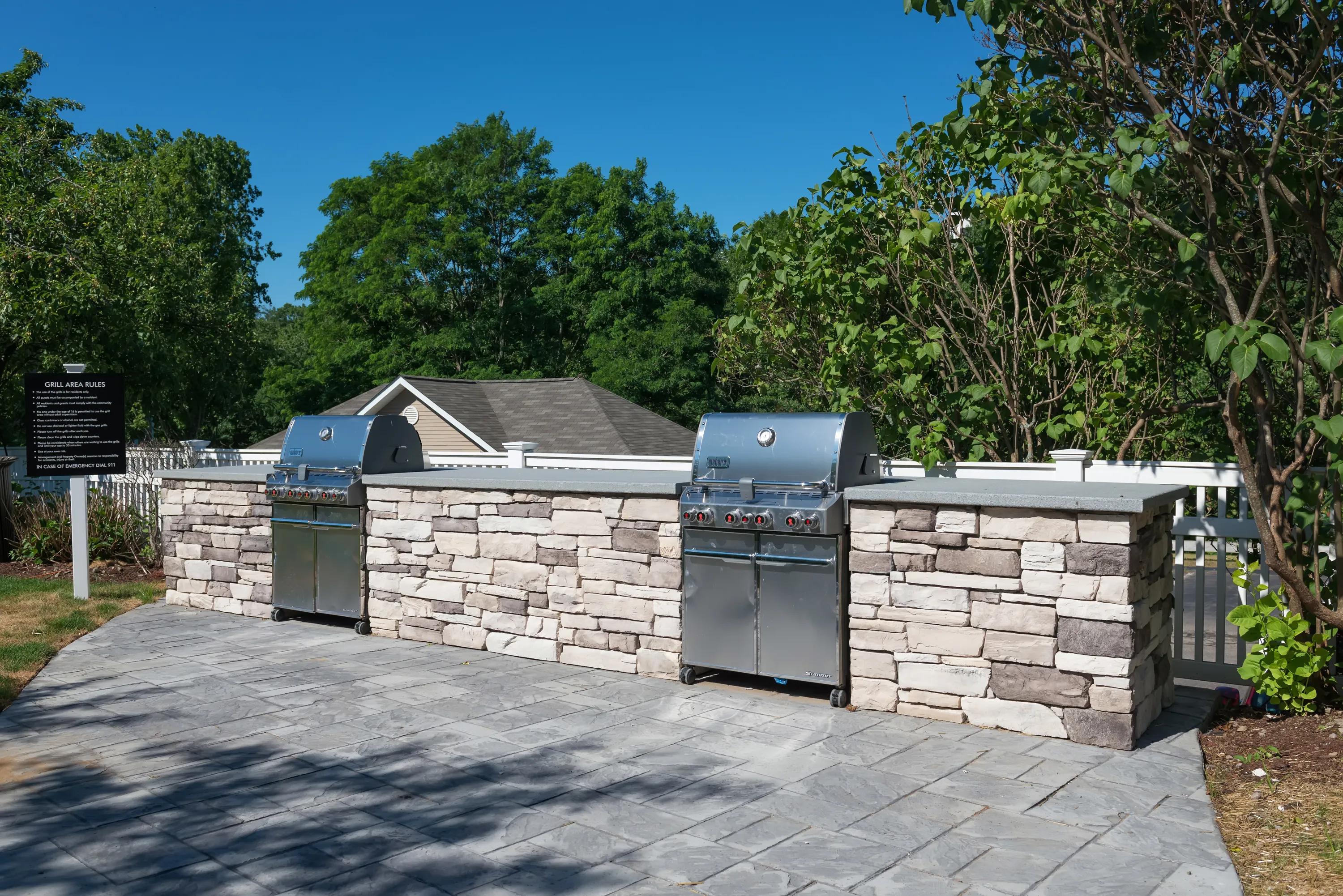 Outdoor courtyard with grilling areas, firepit, and lounge seating Alister Quincy boston apartments ma