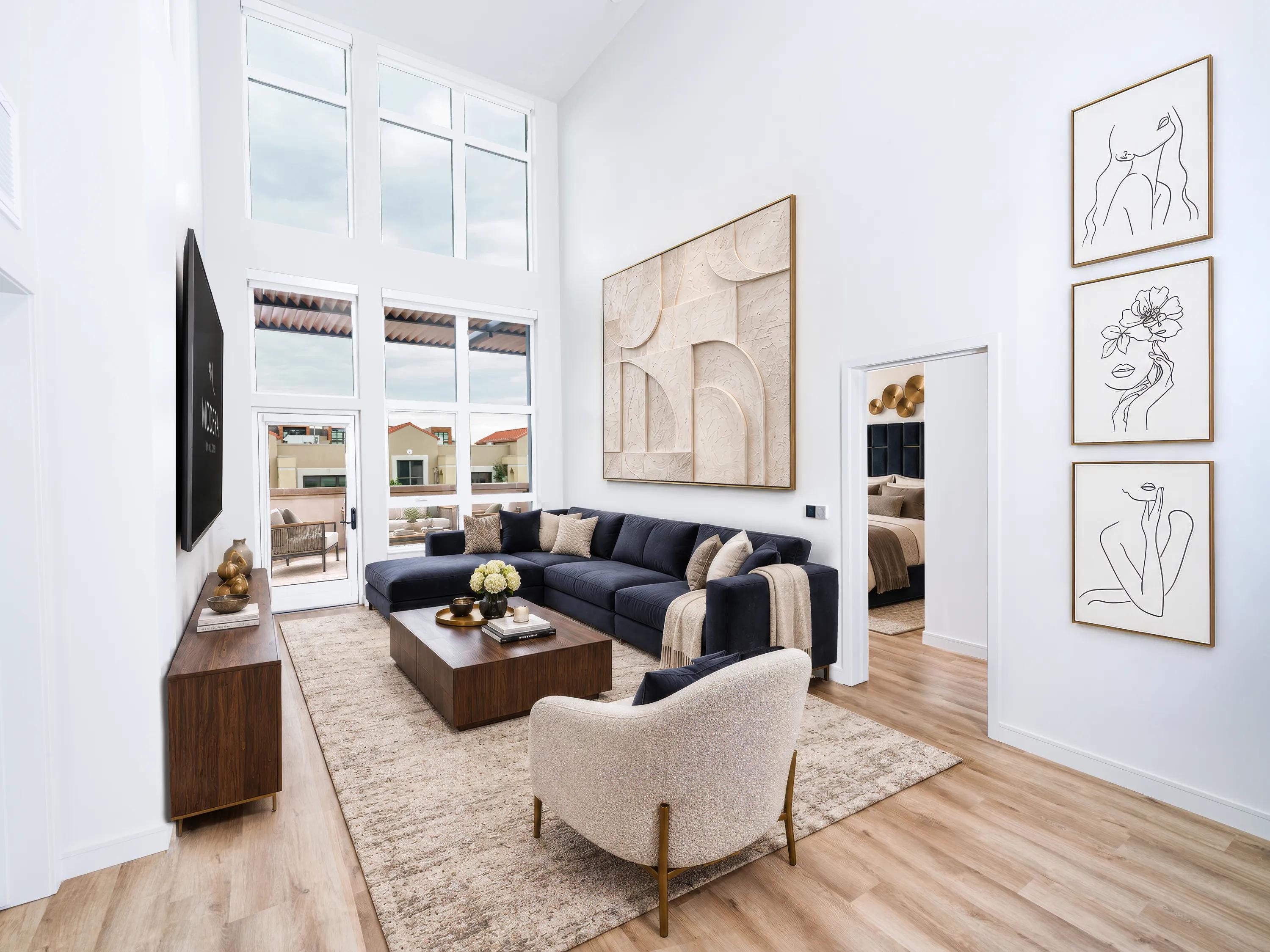 Two-story apartment home with double-height windows, a spacious living room, wood-style flooring, and a lofted floor plan that fills the space with natural light at Modera Second Avenue apartments in Denver, CO.