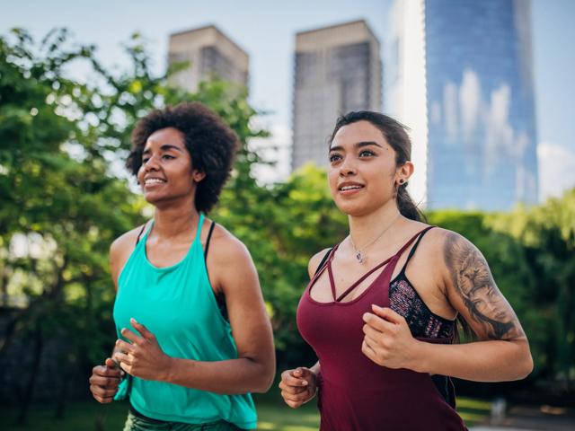 two women running together in green space with city backdrop modera liberty row apartment homes for rent in charlotte nc