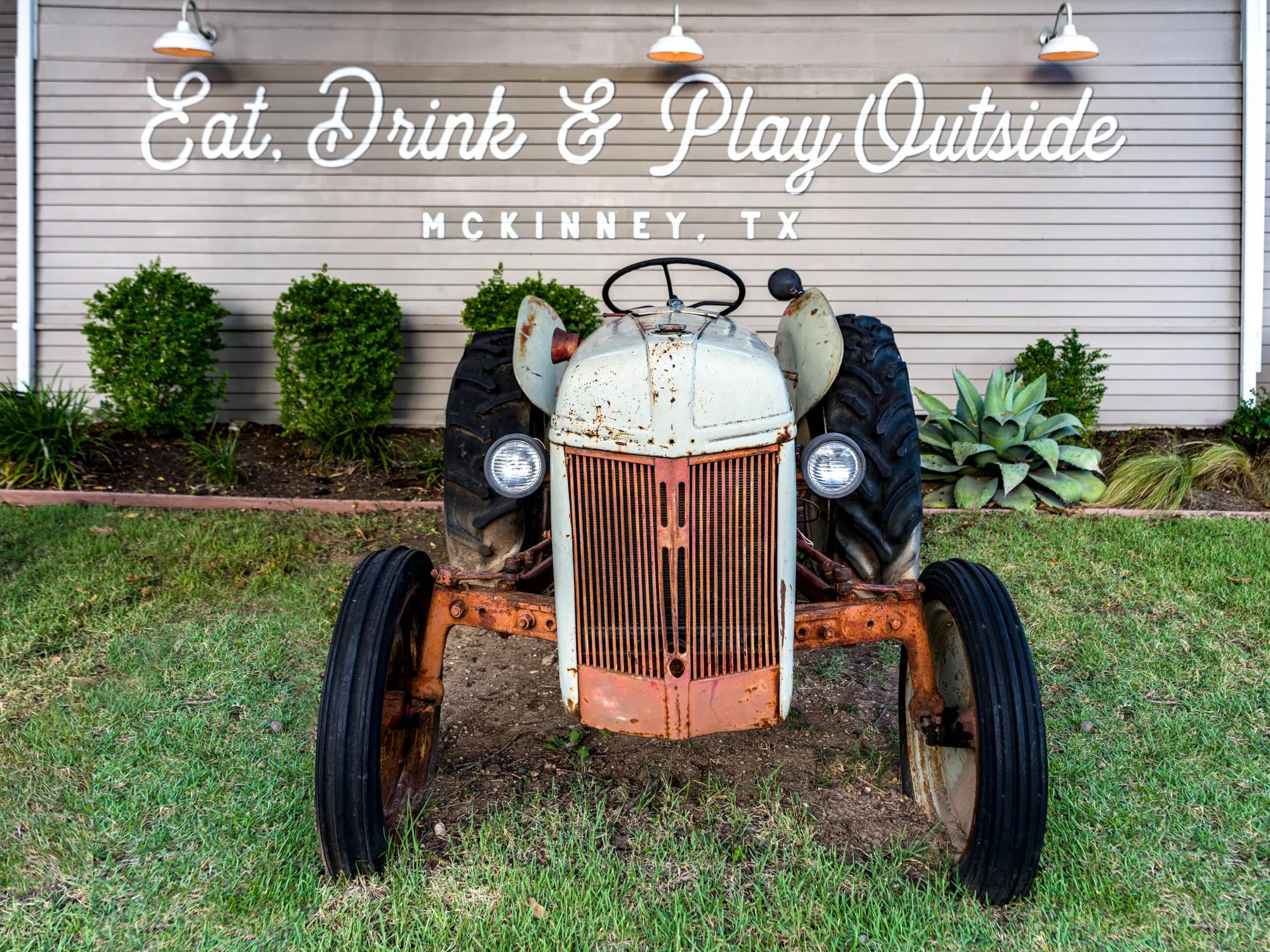 antique tractor on lawn in front of building modera mckinney ridge apartment homes for rent in texas