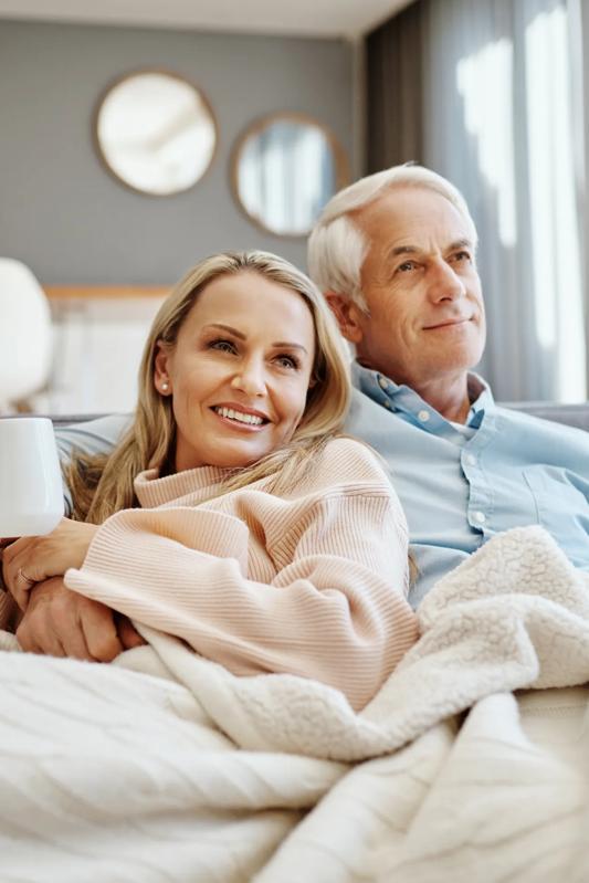 mature couple lounge on couch together smiling and embracing alister quincy apartments