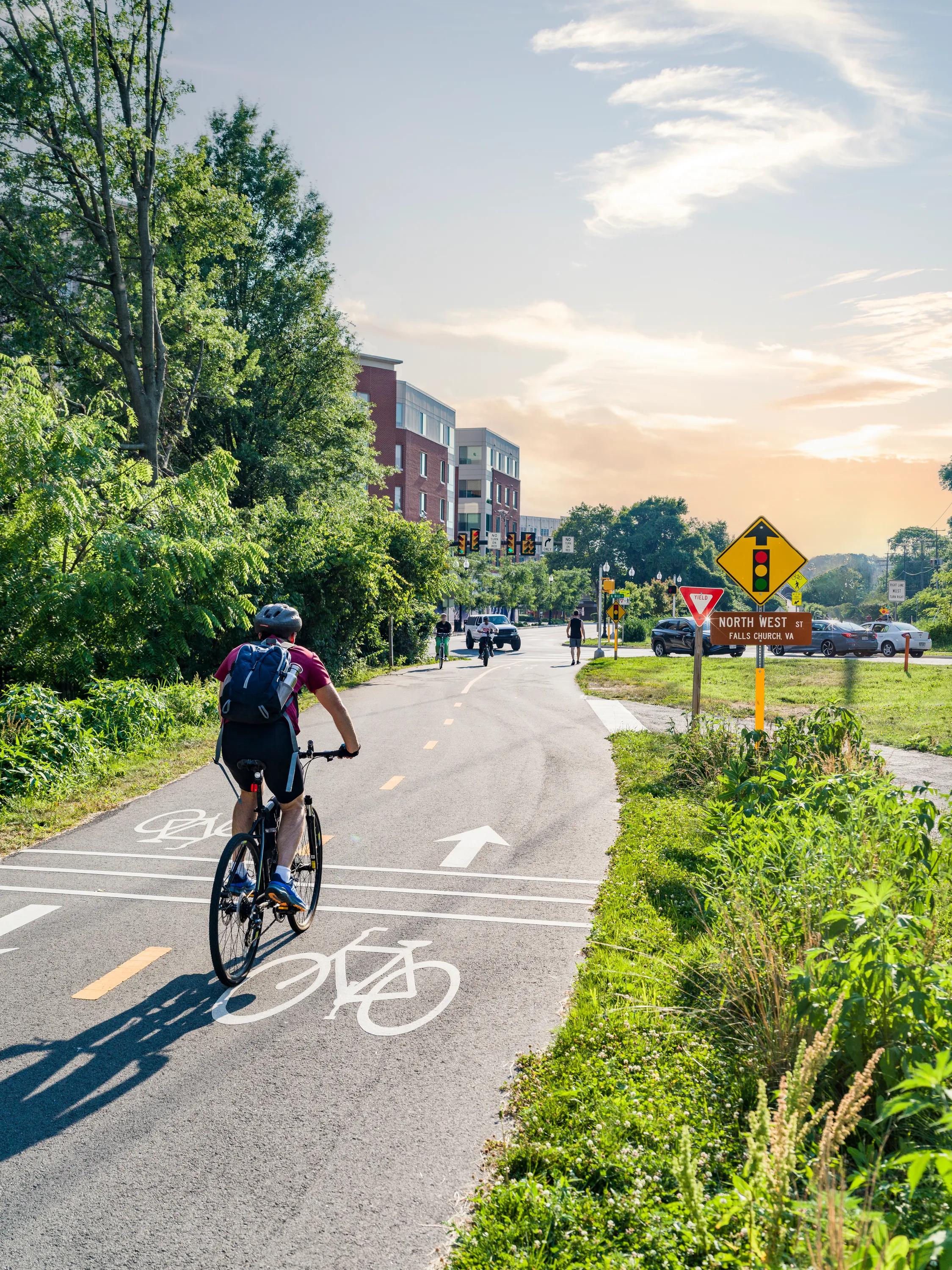 person riding bike on path on sunny day at modera falls church apartment homes for rent in va