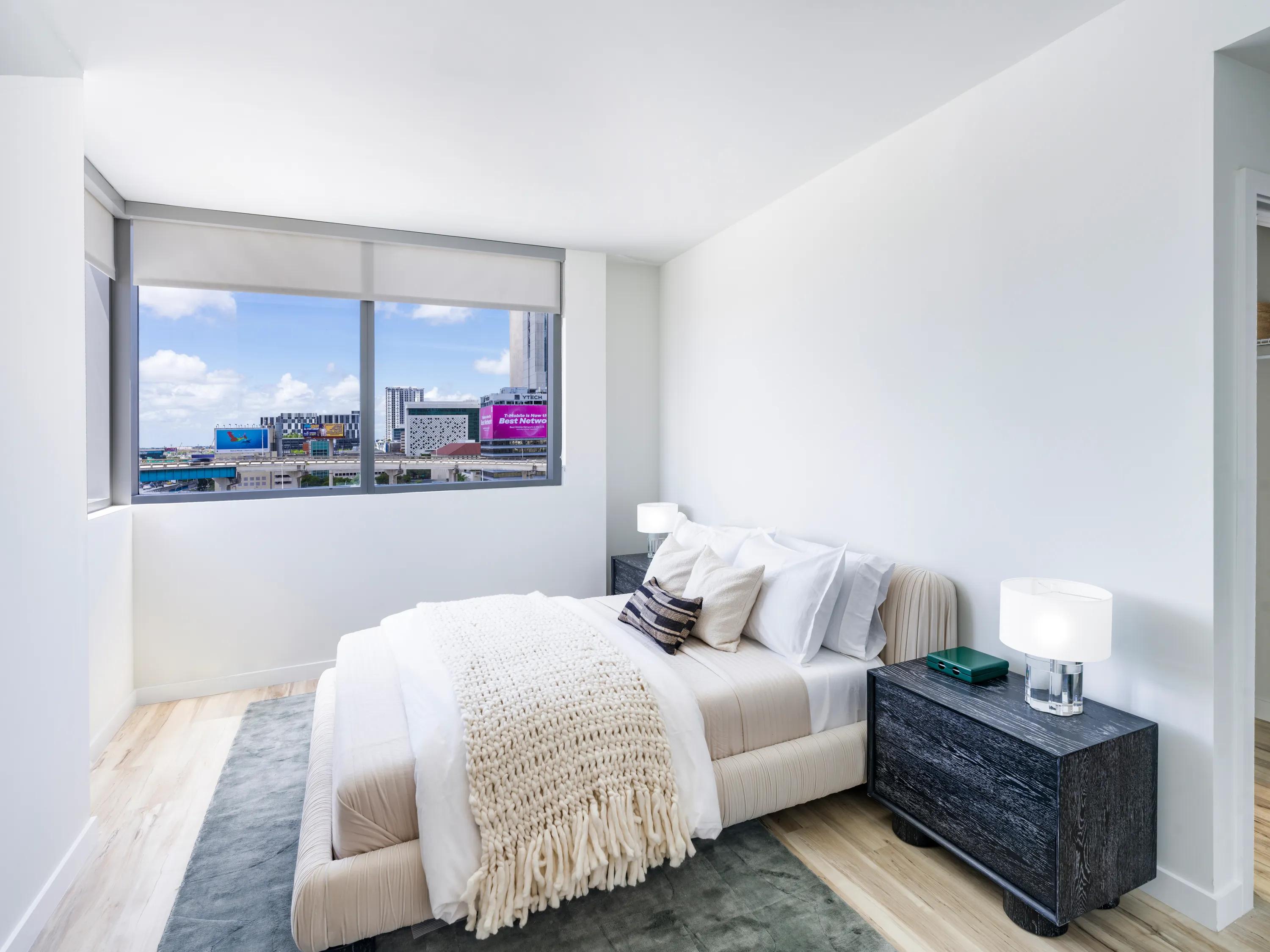 bedroom with tasteful furniture and large window with tv on wall modera riverside apartment homes for rent in miami fl
