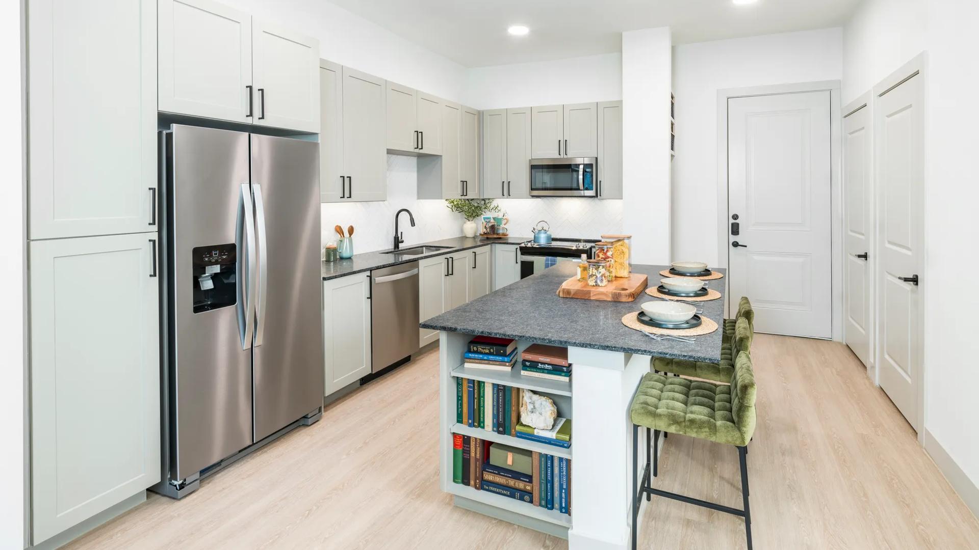 kitchen with large island and stainless steel appliances leading into living area modera mckinney ridge apartment homes for rent in tx
