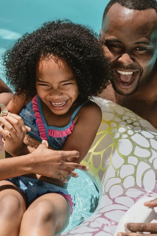 girl and father in pool smiling and playing