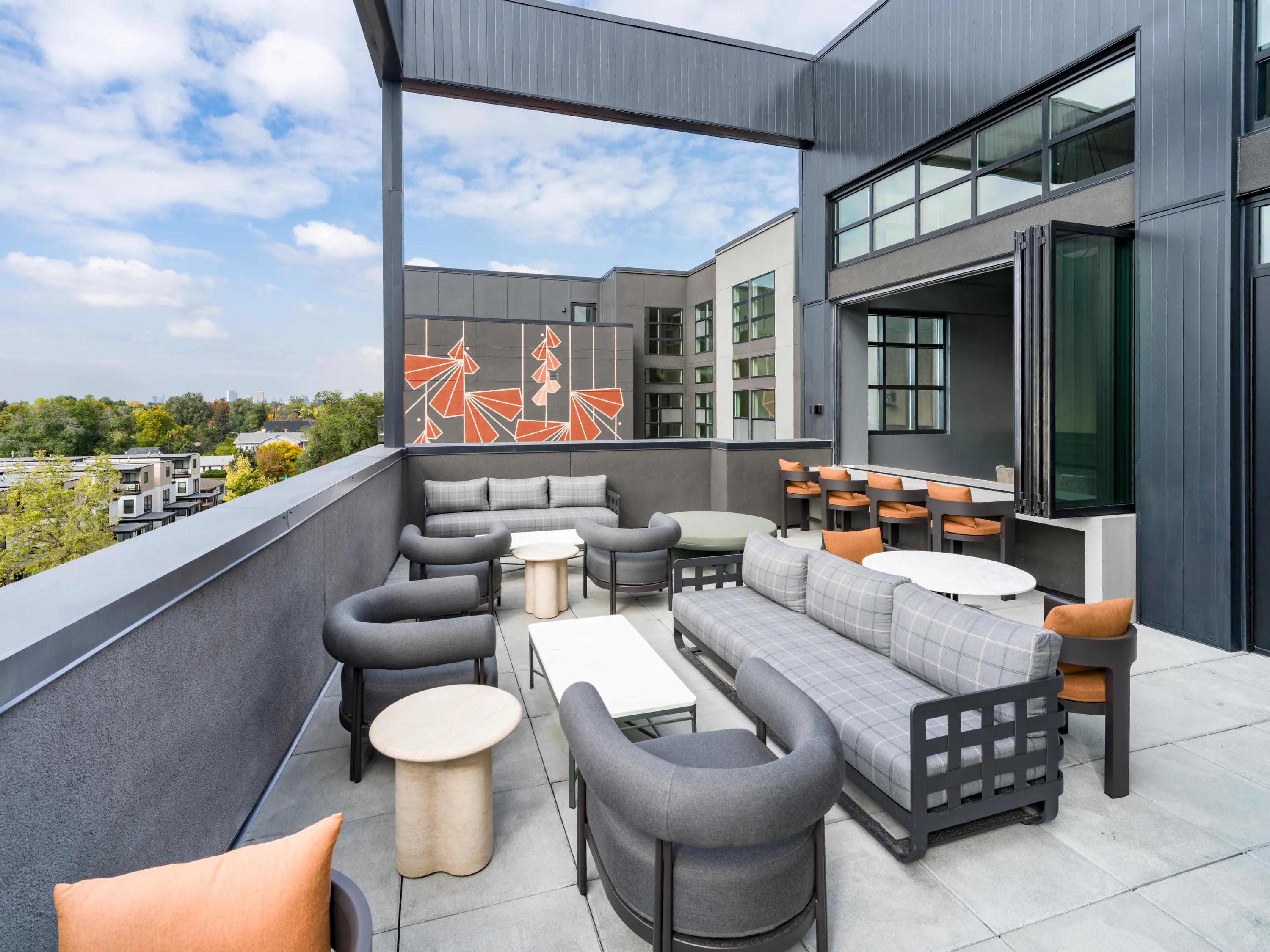 indoor outdoor patio lounge with large tables throughout at modera university park apartment homes for rent in denver co