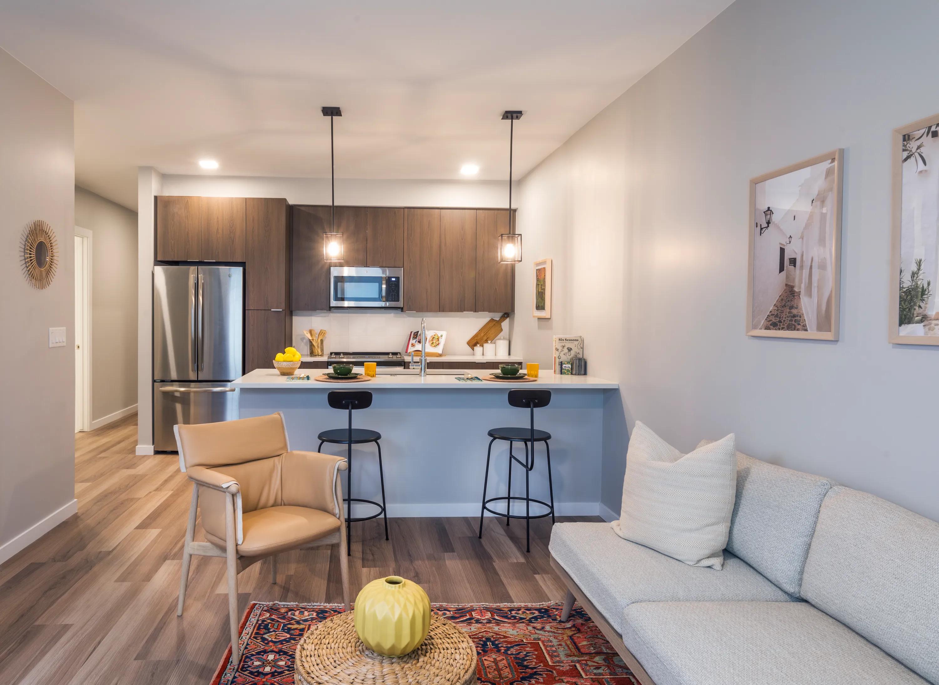 Spacious living room with open concept designer kitchen, espresso cabinetry, and stainless steel appliances modera lohi apartments in denver co