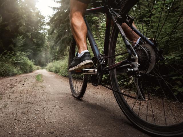 Close up of a biker riding a bike through the forest road