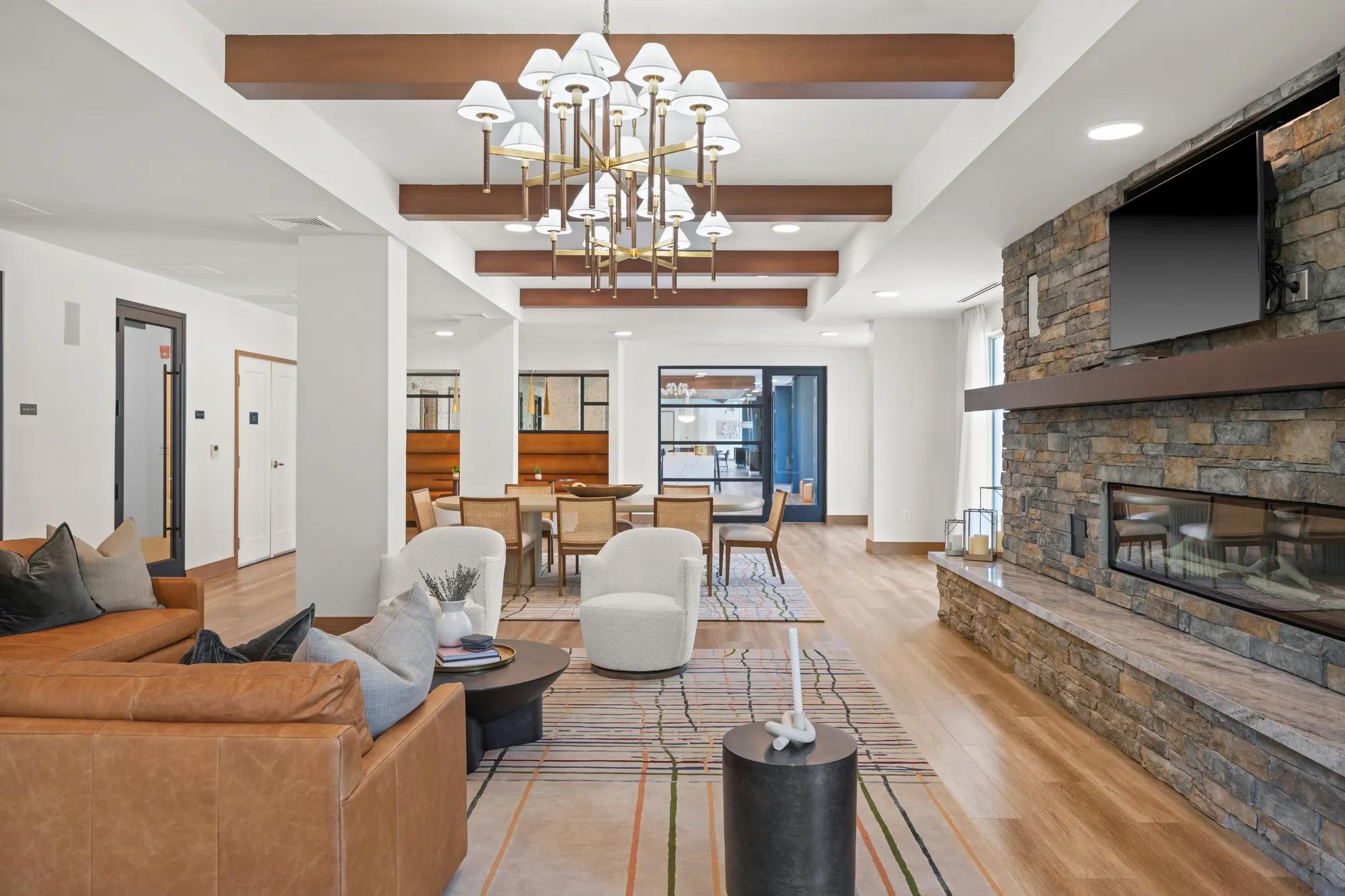 clubroom filled with couch, chairs, and dining table at modera newton apartment homes for rent in ma