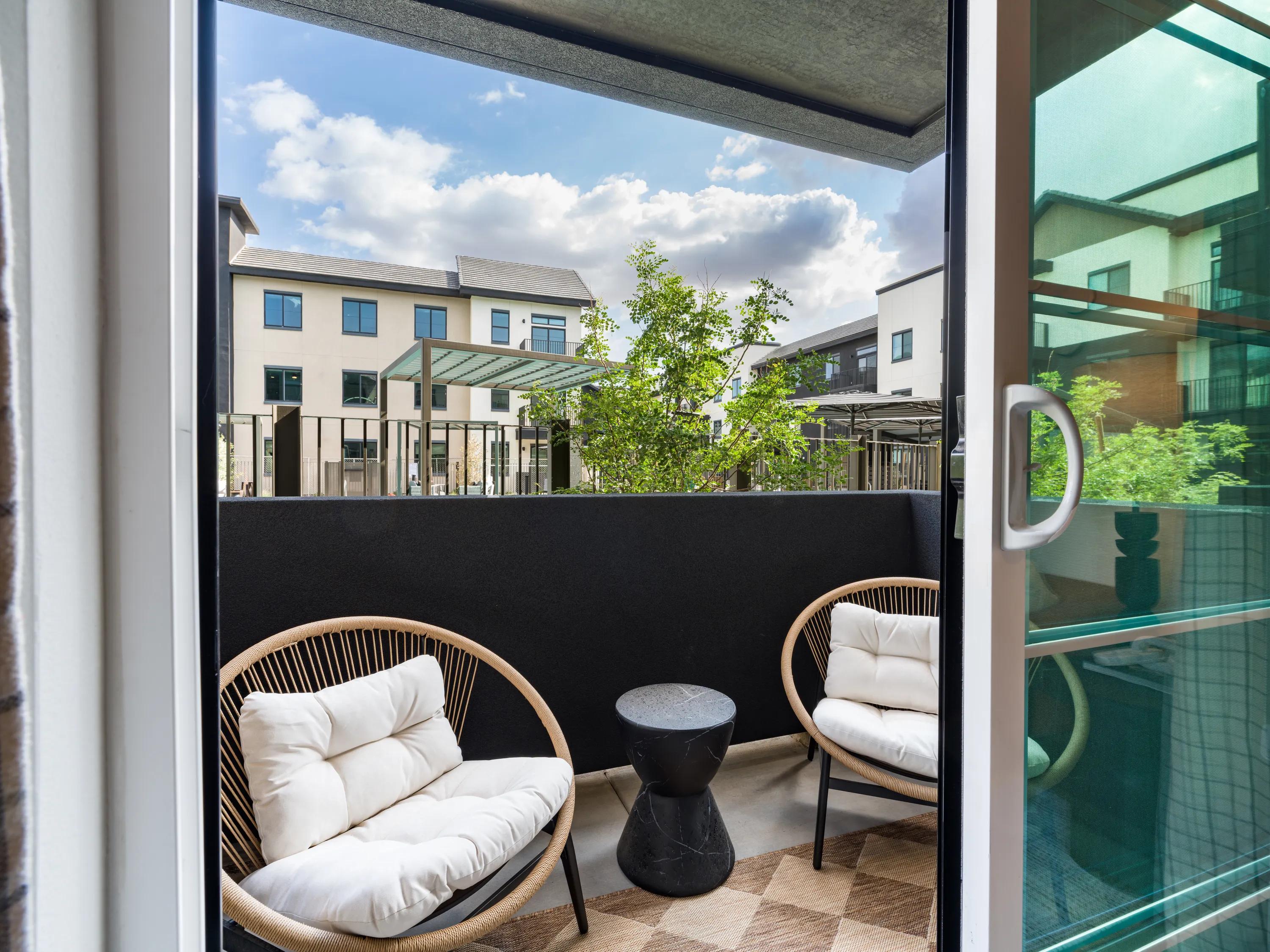 Private apartment balcony with outdoor lounge seating, contemporary finishes, and views of the community courtyard at apartments in Chandler, AZ.