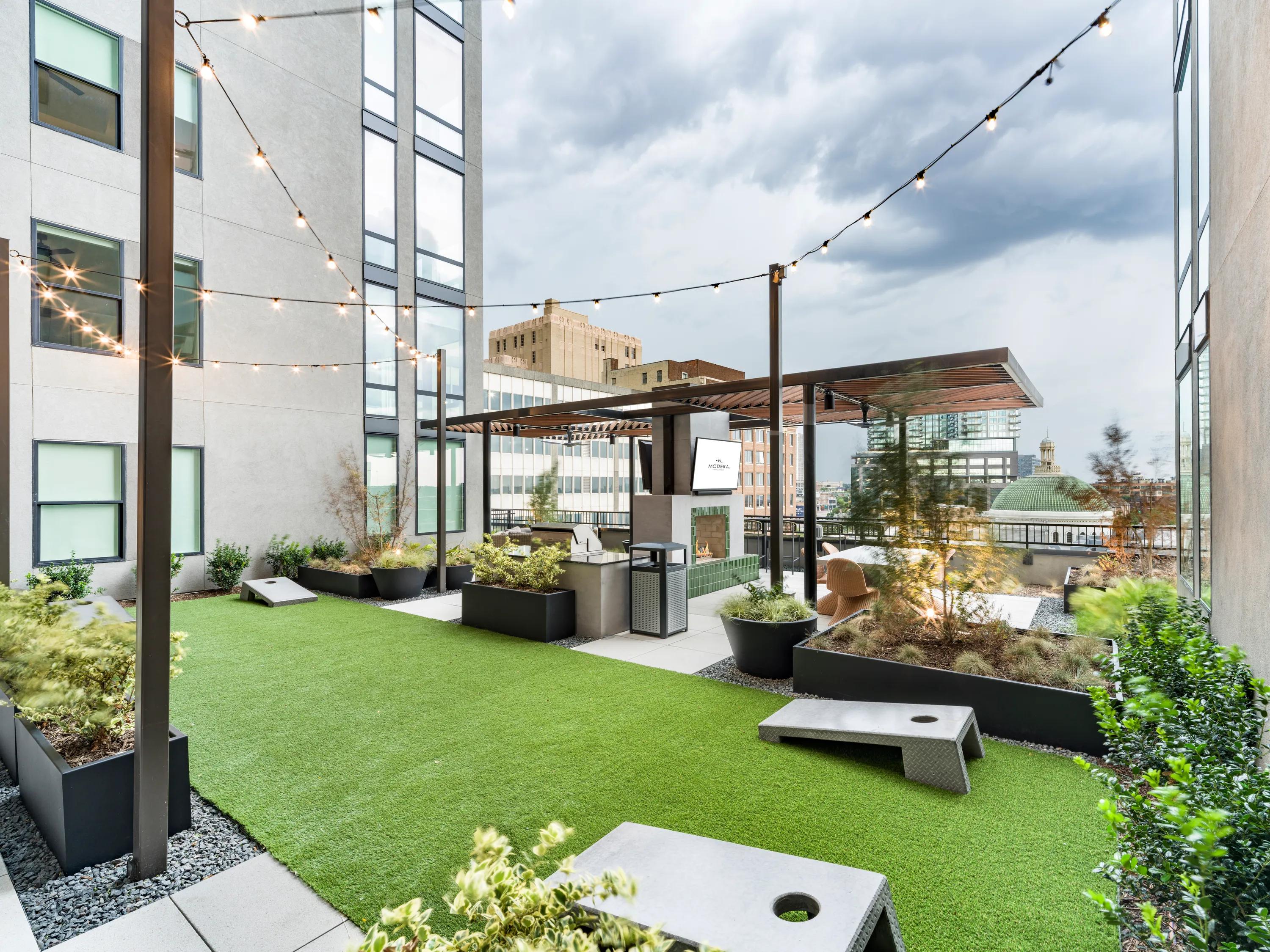 cornhole and grass and fireplace with string lights amenity space modera st paul apartment homes for rent