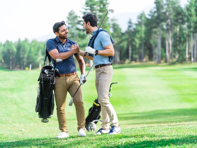 two men golfing and shaking hands on course with clubs modera liberty row apartment homes for rent in charlotte nc