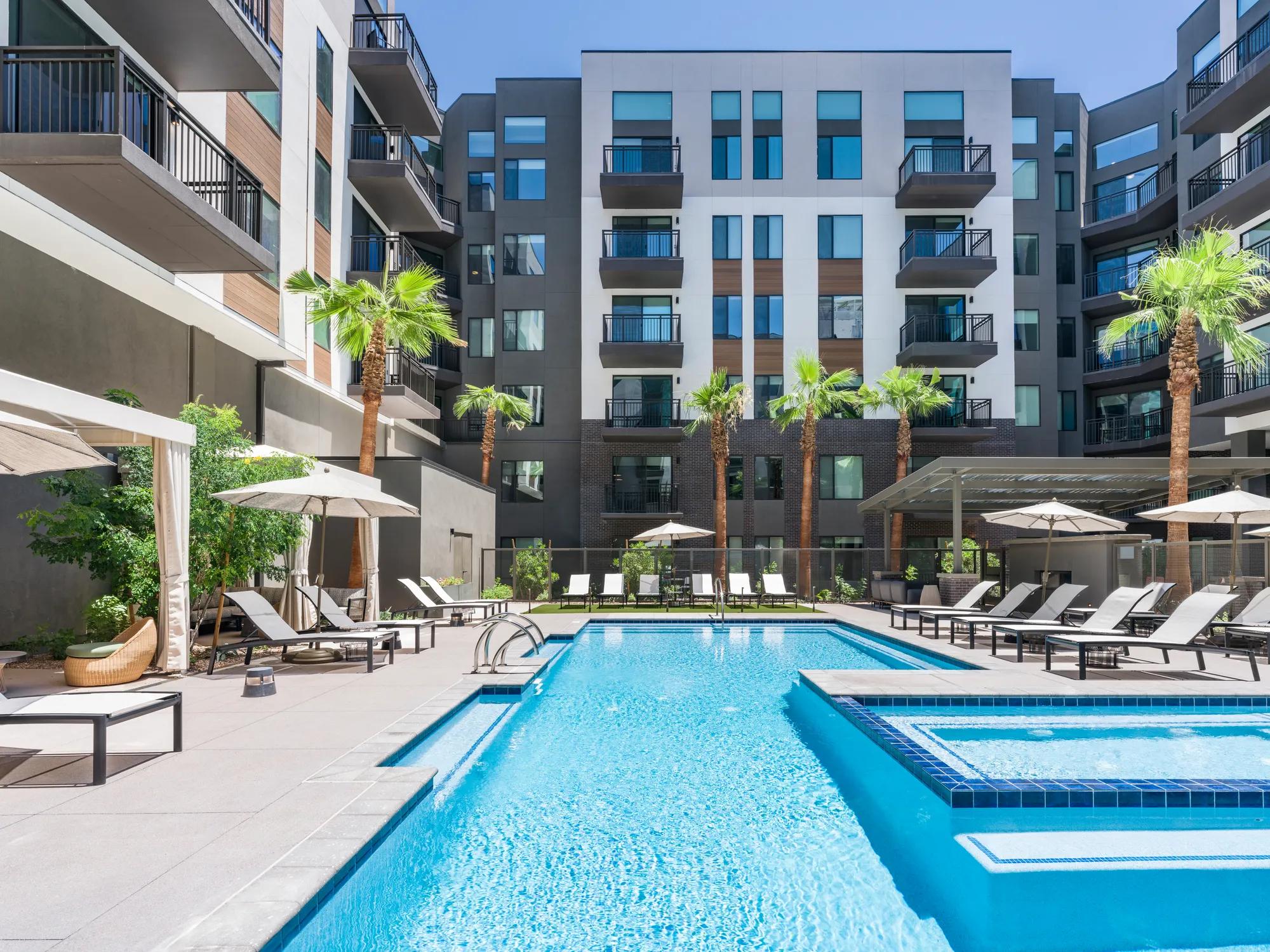 large pool in courtyard with lounge seating and umbrellas at modera scottsdale apartment homes for rent in scottsdale az