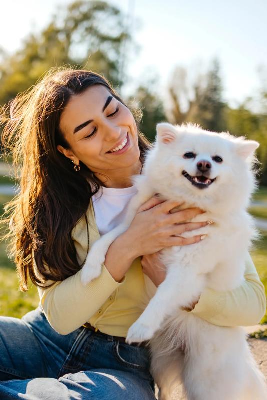 young woman with white dog sitting outside at a park nearby modera marmalade in salt lake city apartments pet friendly