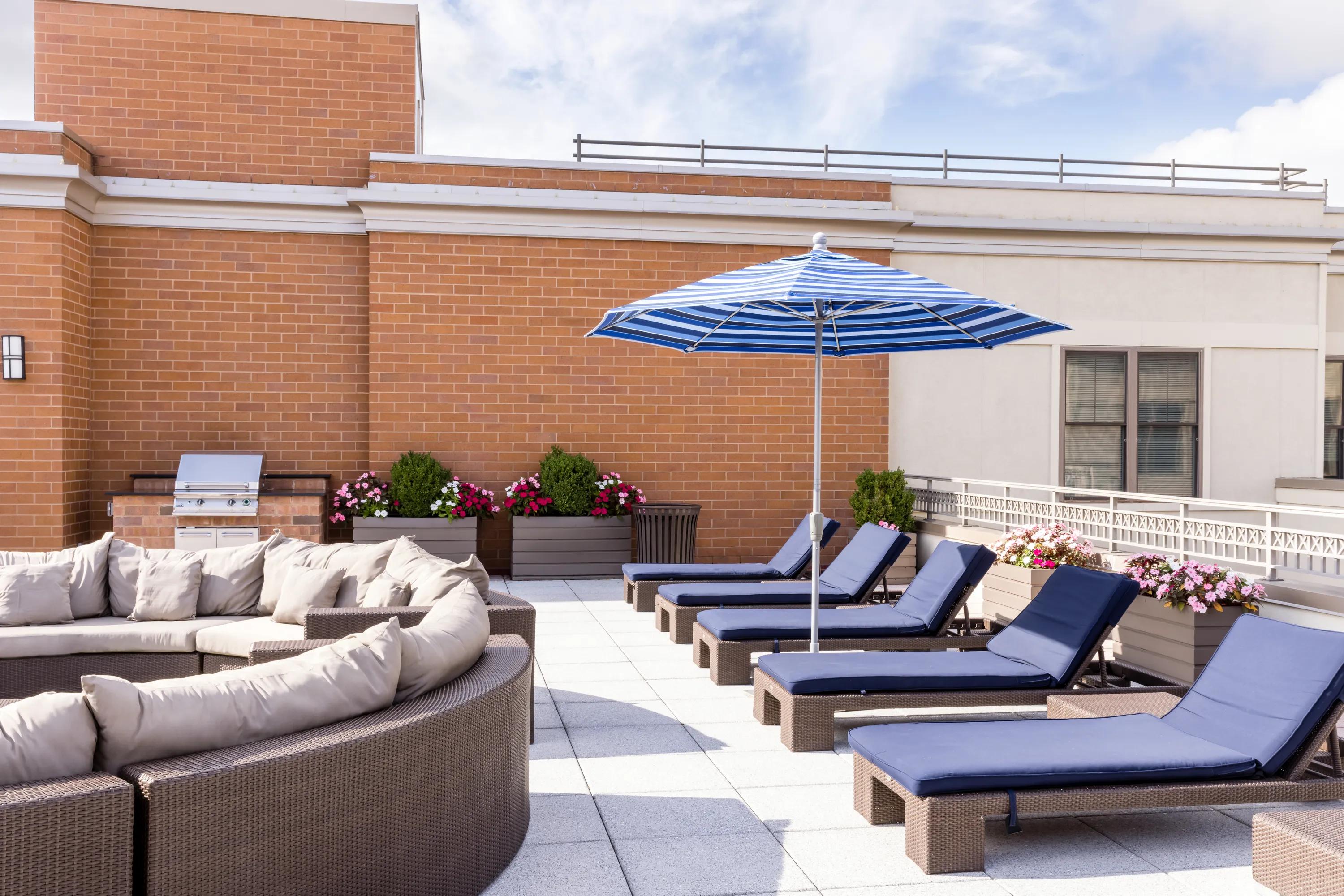 lounge seating with umbrella on rooftop adjacent to bbq metropolitan at 40 park apartment homes for rent in morristown nj