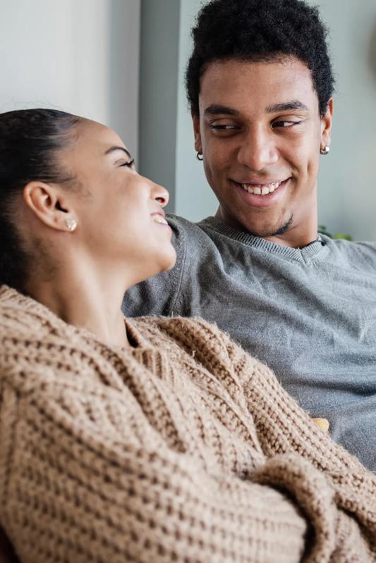 couple sitting on couch looking at each other lovingly