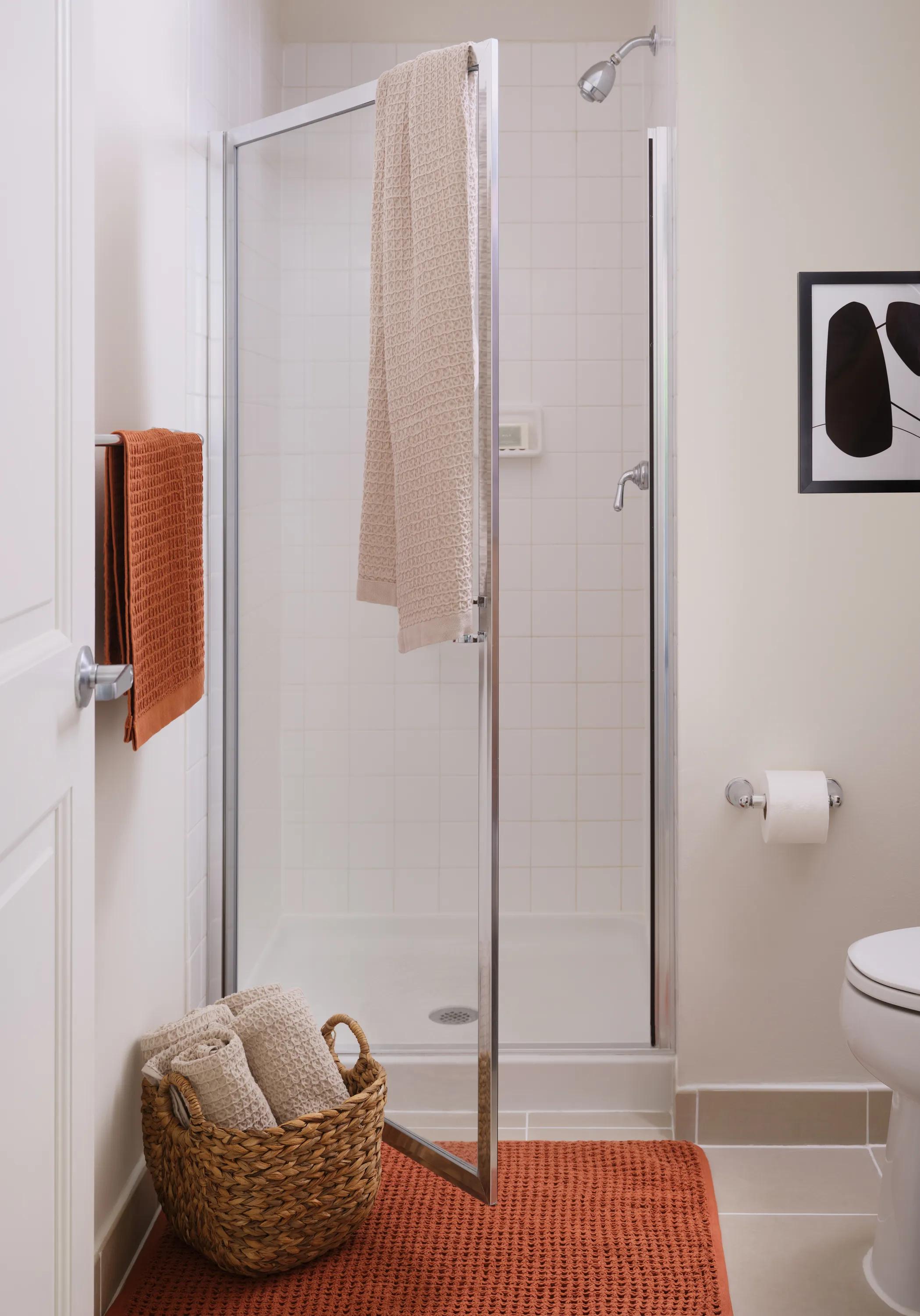 glass enclosed shower with rust colored towels and rug metropolitan at 40 park apartment homes for rent in morristown nj