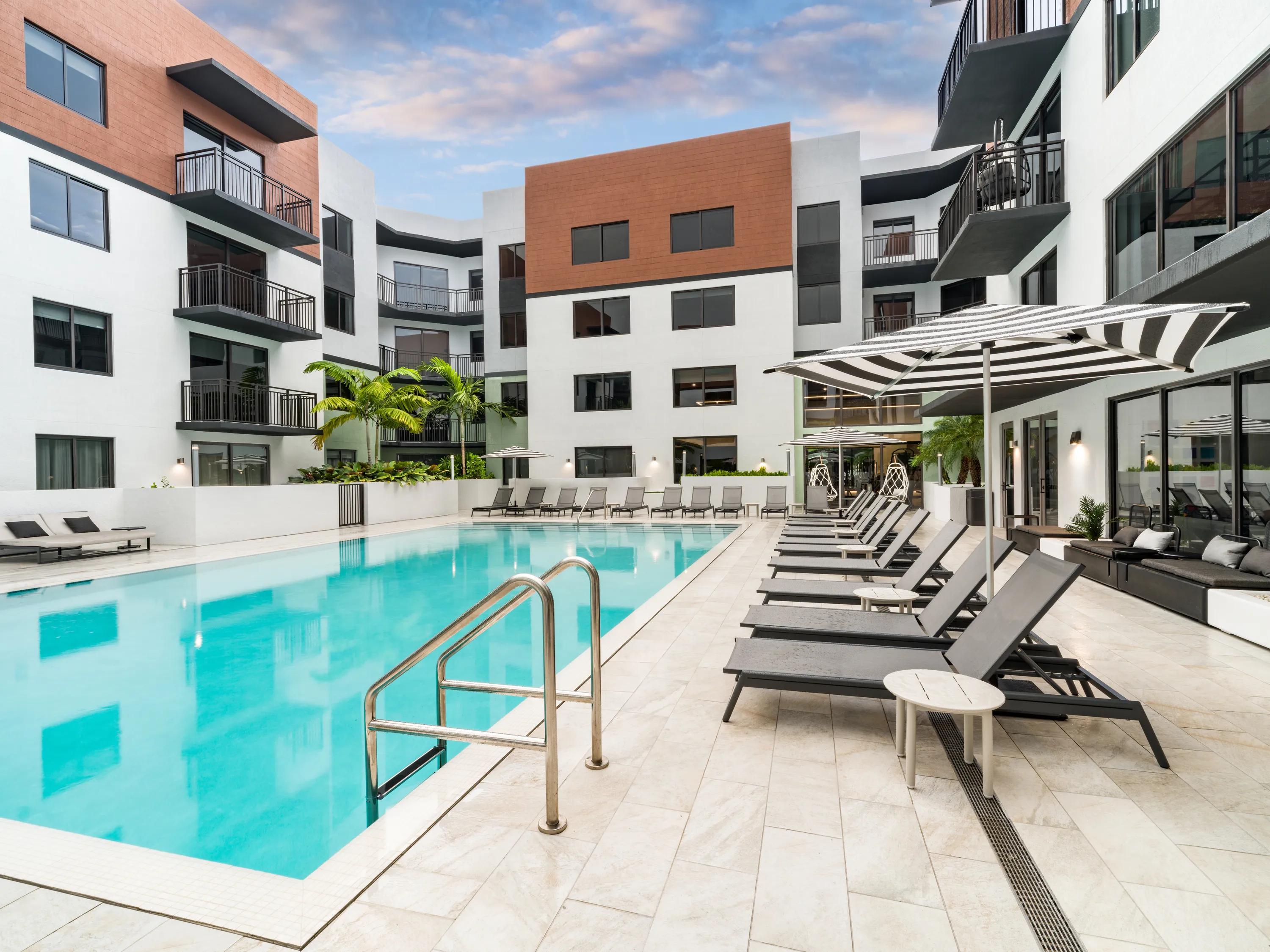 Resort-style pool courtyard with sun loungers, shaded seating modera coral springs phase 2 apartments in coral springs fl