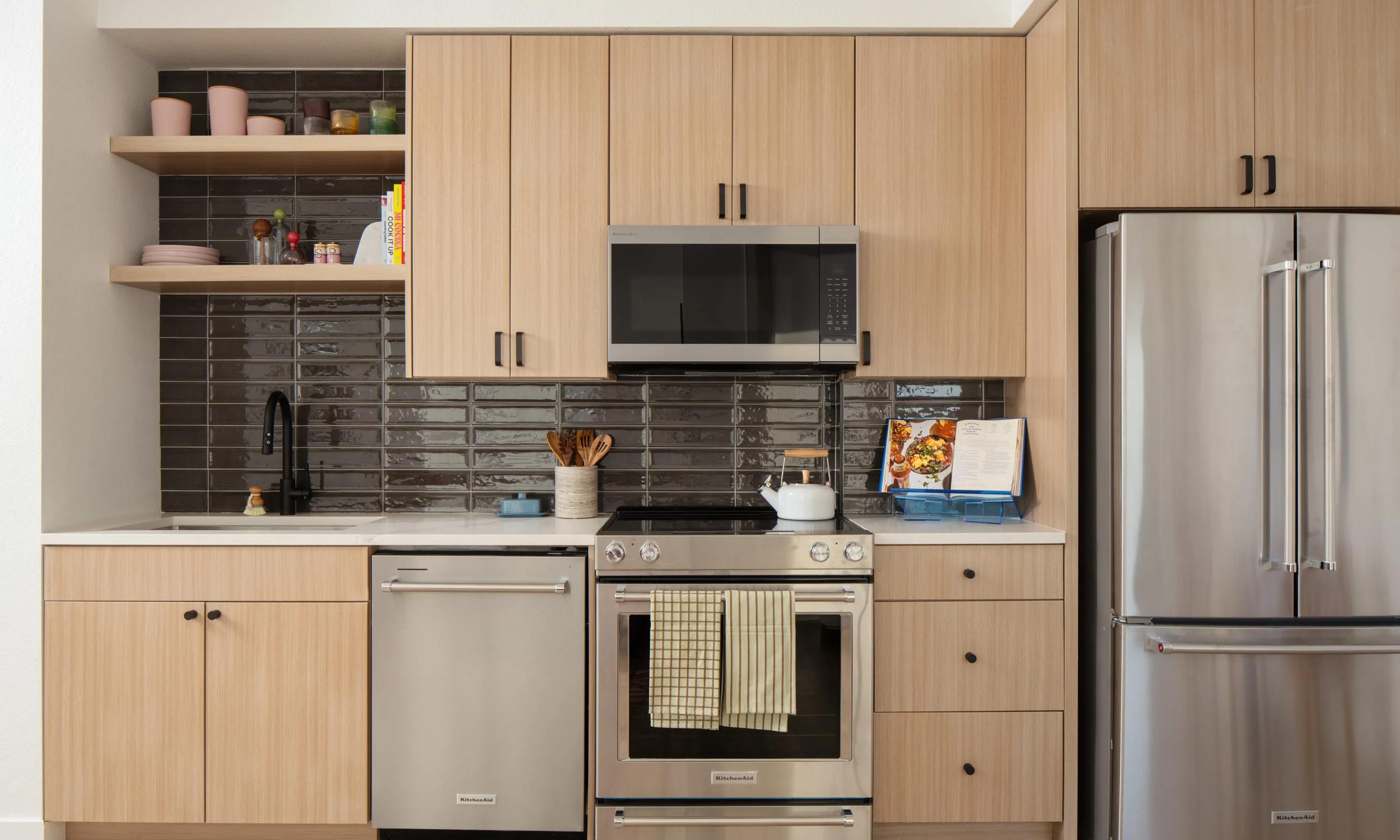 light wood kitchen with stainless steel appliances and black tile backsplash modera rio salado apartment homes for rent in tempe az