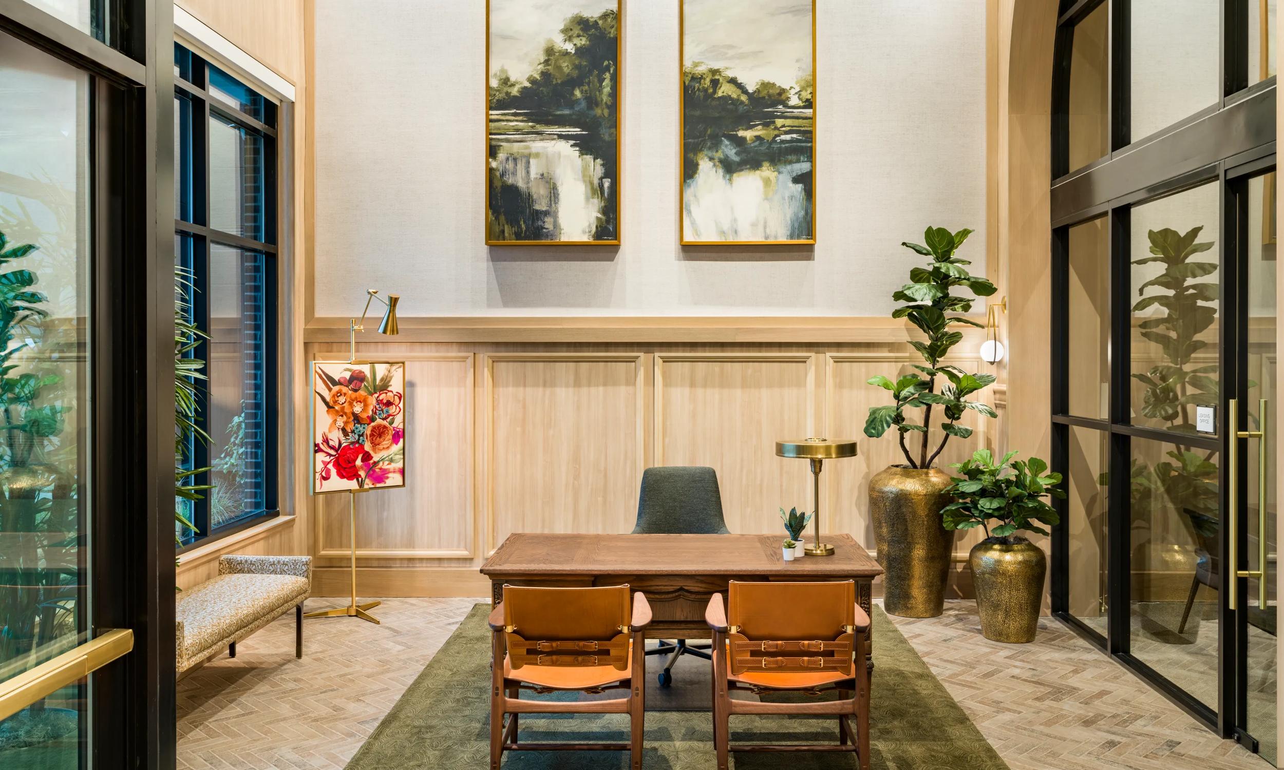 Elegant office space with large arched windows, chic artwork, and luxurious dark wood furniture. Features a cozy seating area with natural light and modern decor.