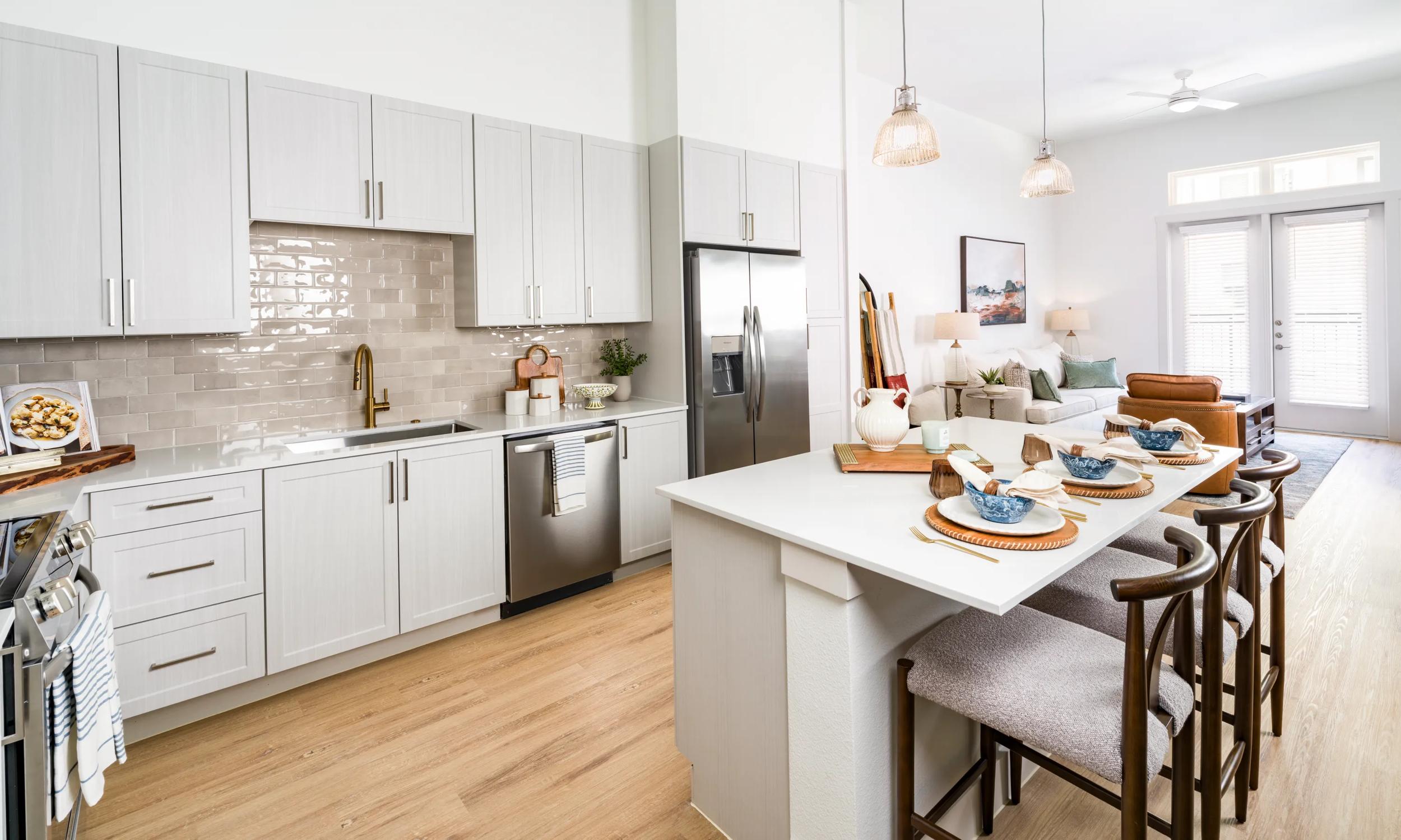 Open kitchen with quartz countertops, pendant lighting, and bar seating flowing into a connected living area filled with natural light modera walsh heights apartments