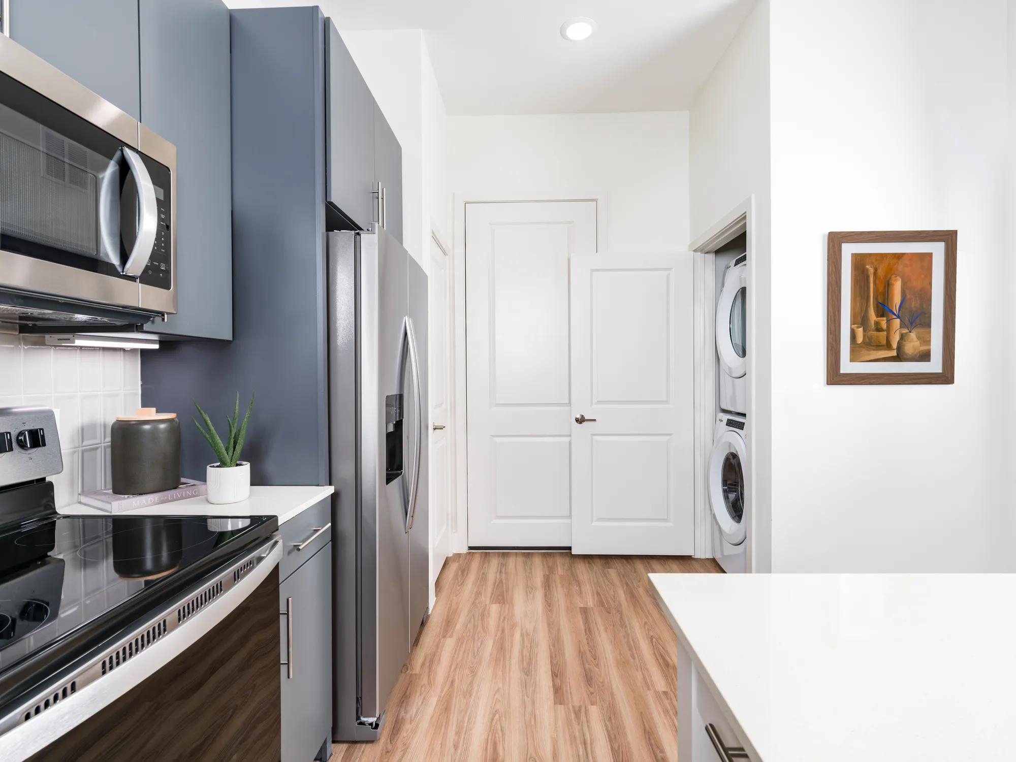 kitchen with gray custom cabinetry, stainless steel appliances, custom backsplash, and quartz countertops
