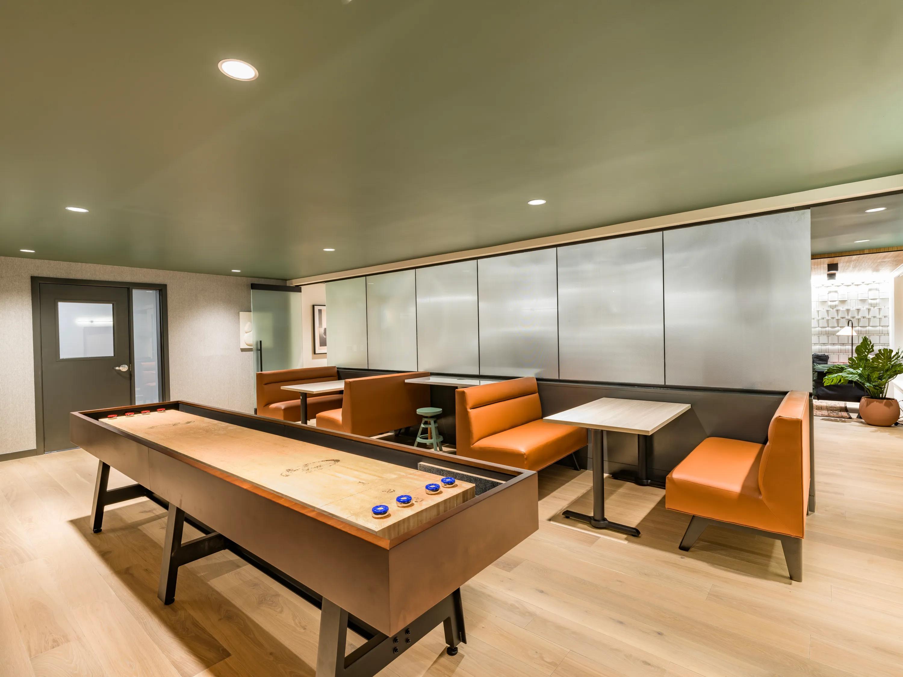 gaming lounge featuring shuffleboard, tv areas, and plenty of seating
